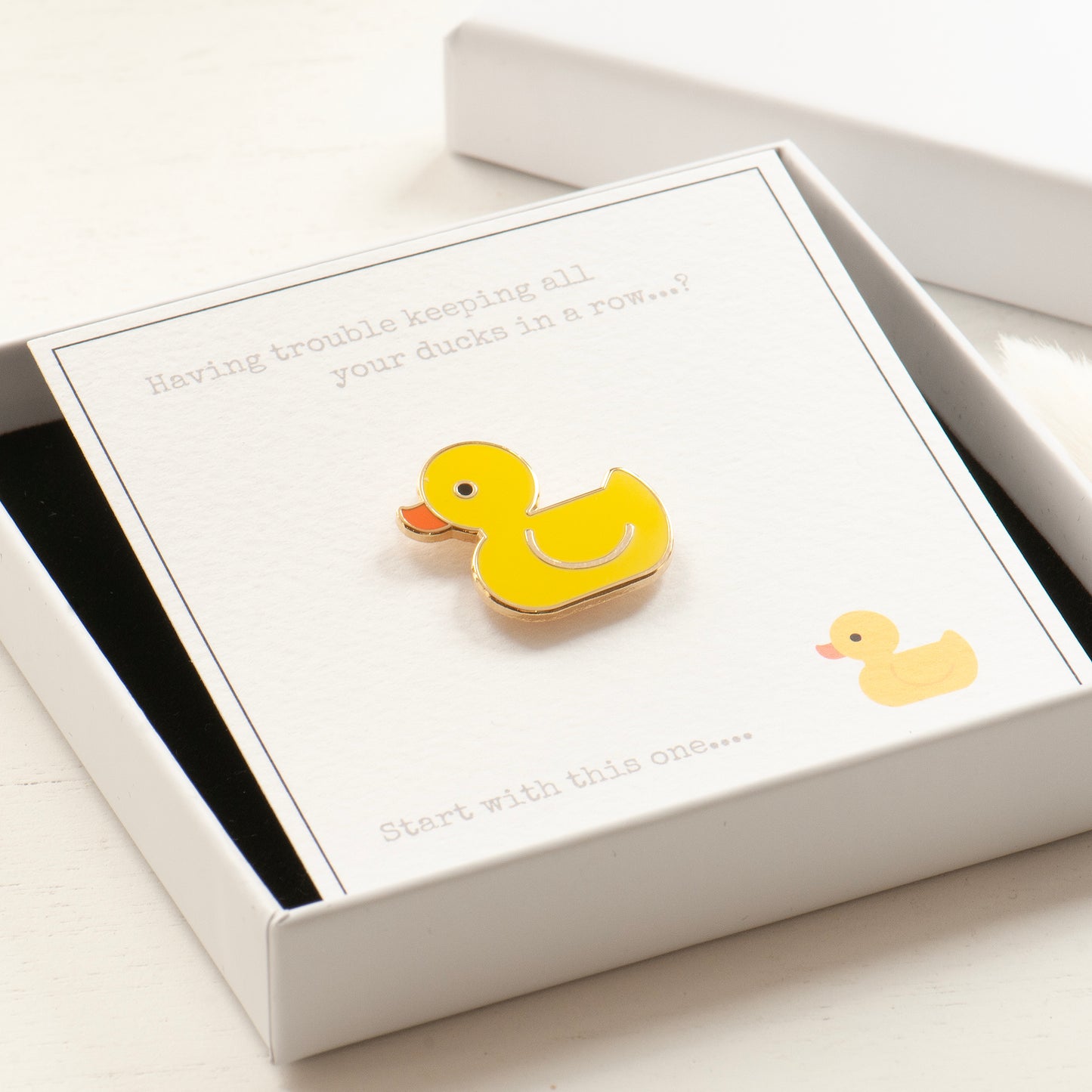 Ducks in a row gift card and yellow cute rubber duck pin in a white elegant gift box, ready for gifting