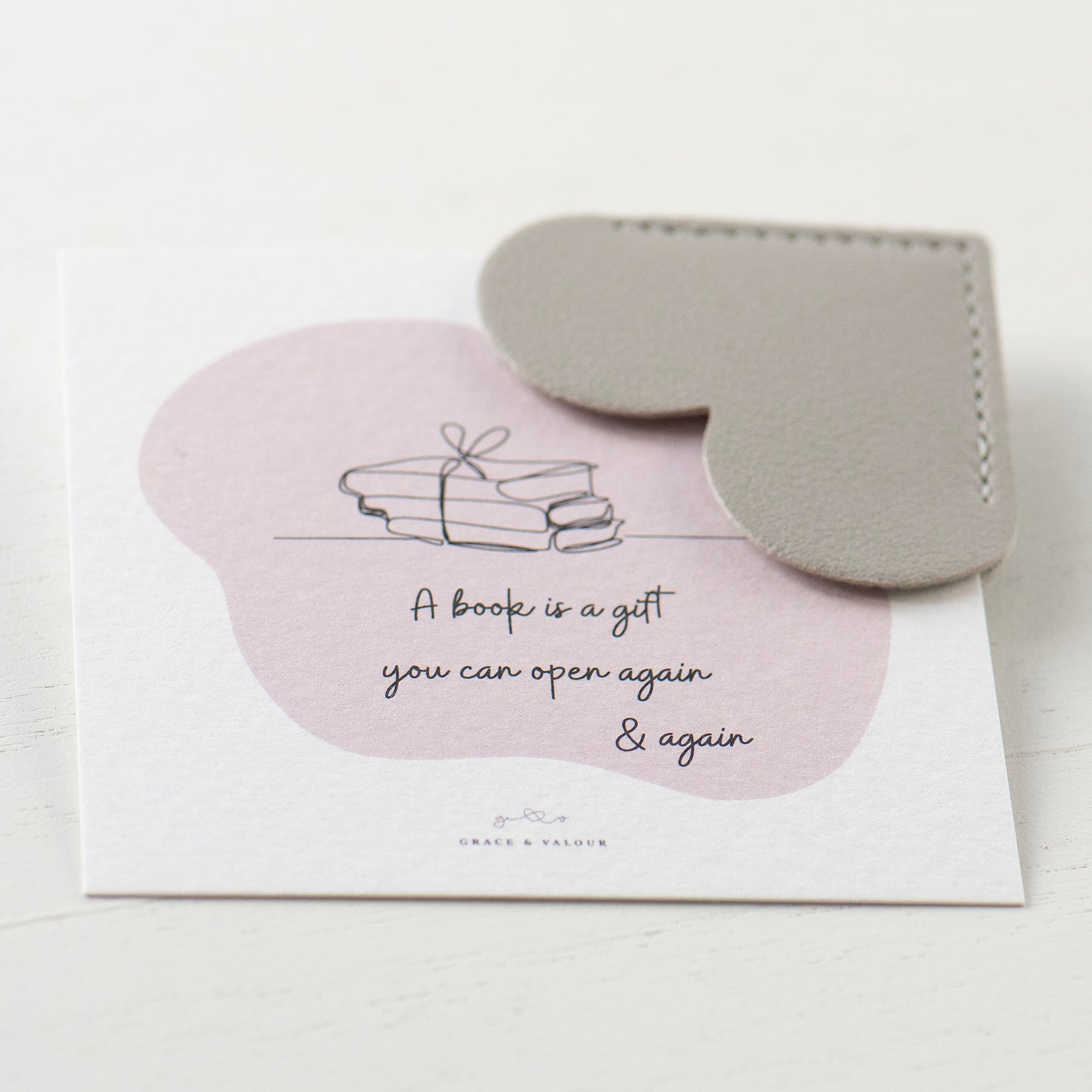 Grey heart shaped bookmark on bespoke gift card which reads 'A book is a gift you can open again and again'