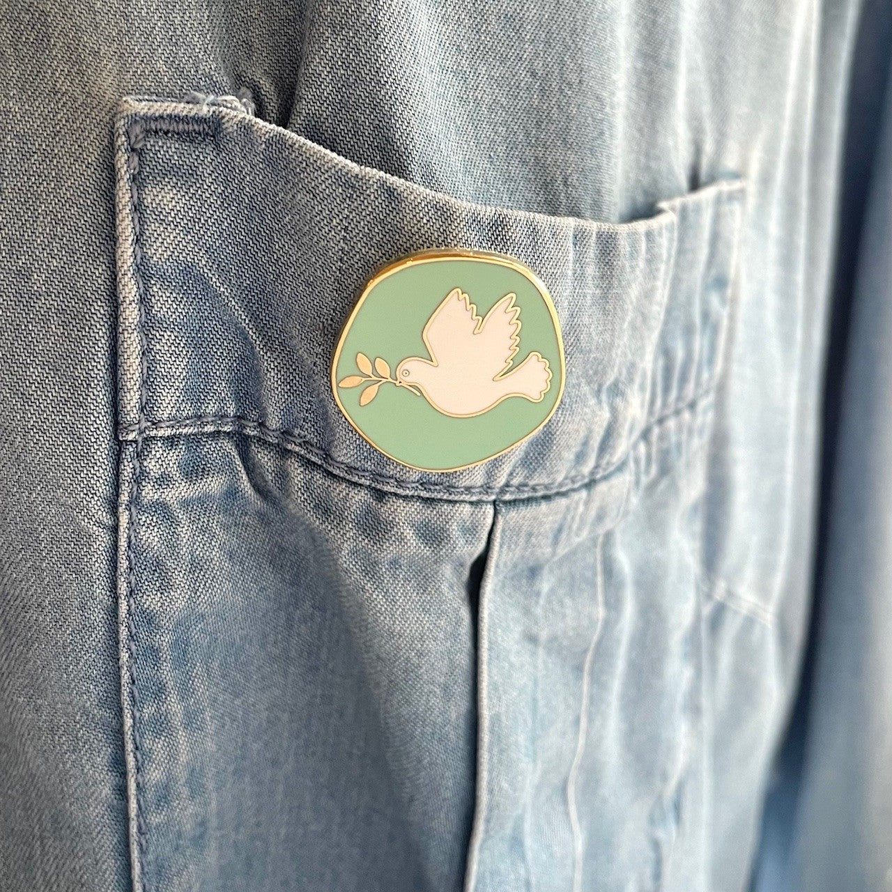 Mint green dove of peace lapel pin worn as a pocket accessory.
