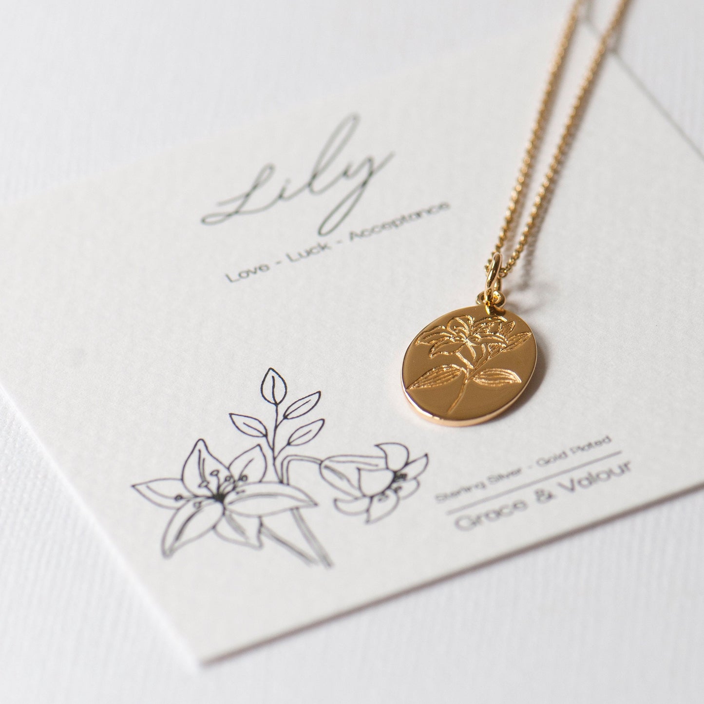 Gold plated engraved lily flower necklace, made from sterling silver and arrives on our bespoke Lily flower giftcard with information on the meanings of the lily flower - floriography. Designed by Rachel - Grace & Valour