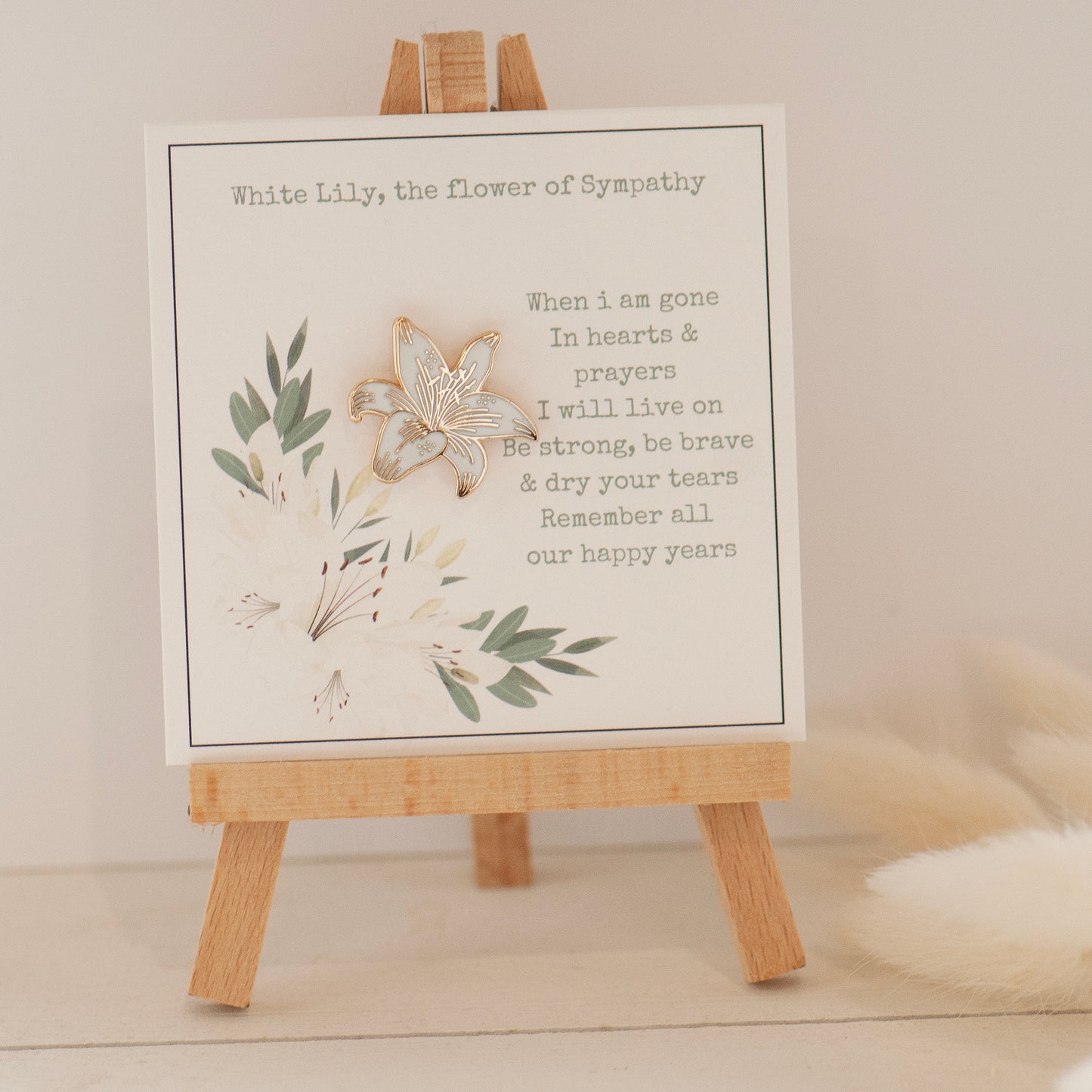 White and gold lily pin, on bespoke gift card which reads 'When i am gone, in hearts & prayers i will live on. Be strong, be brave & dry your tears. Remember all our happy years. Designed by Rachel - Grace & Valour