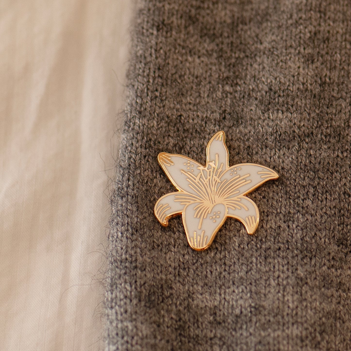 White and gold stargazer lily enamel pin on lapel showing gold detailing