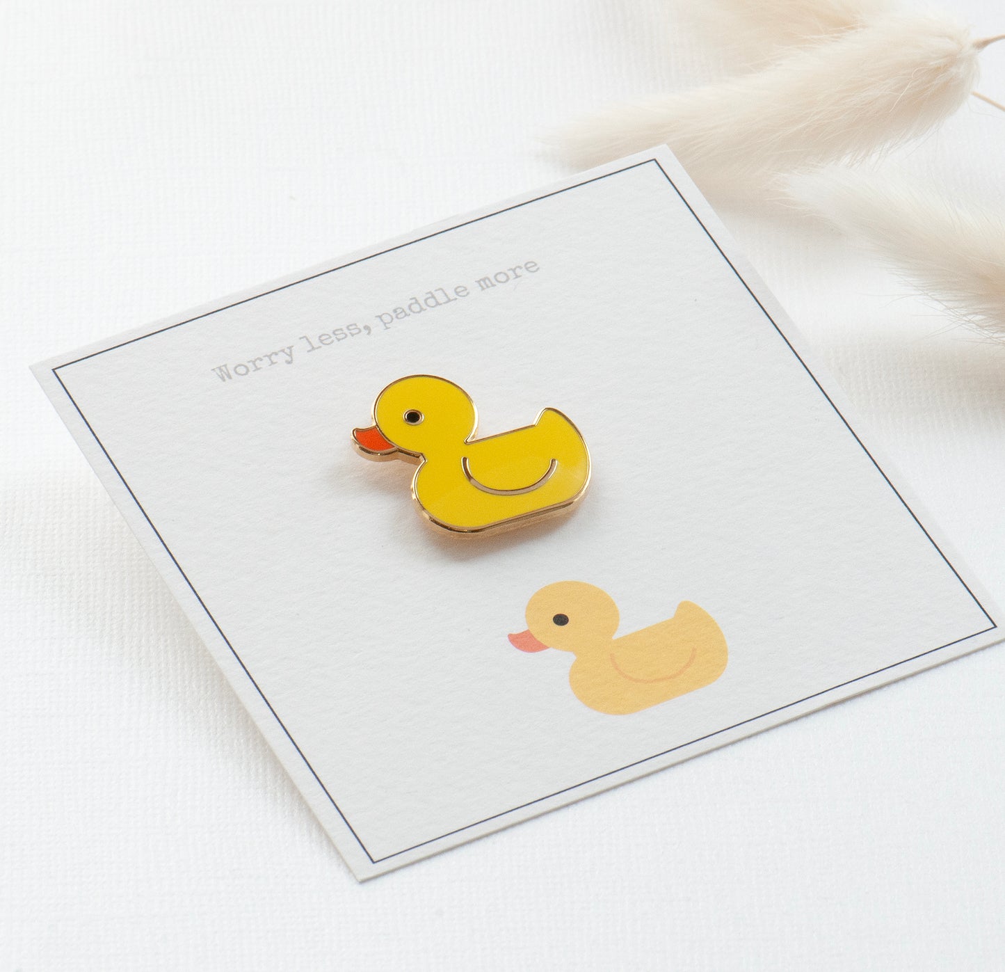 Yellow rubber duck enamel pin on my bespoke gift card which reads 'Worry less, paddle more'