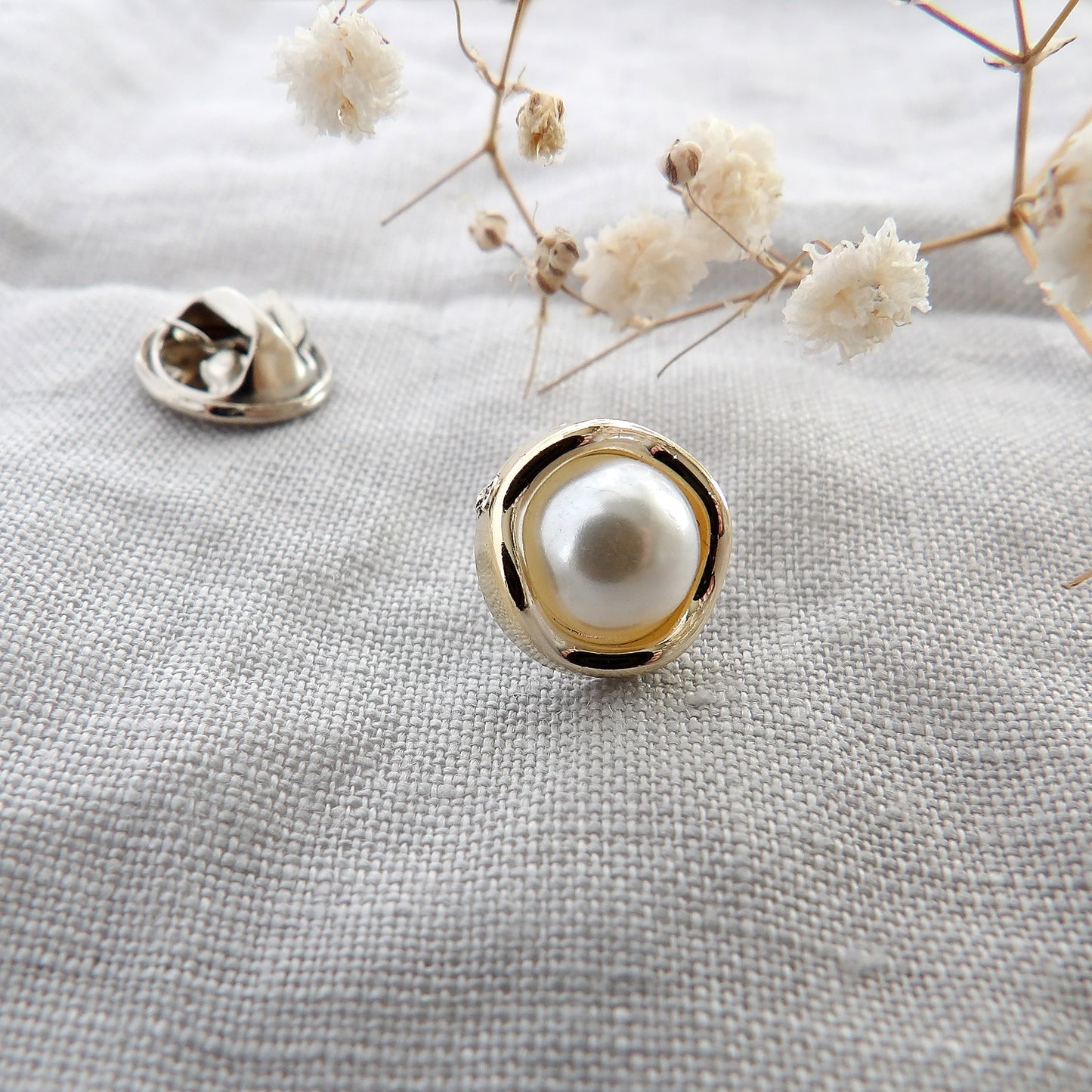 close up of pearl modesty pin with gold curvy surround