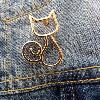 Gold cat outline brooch on denim jacket