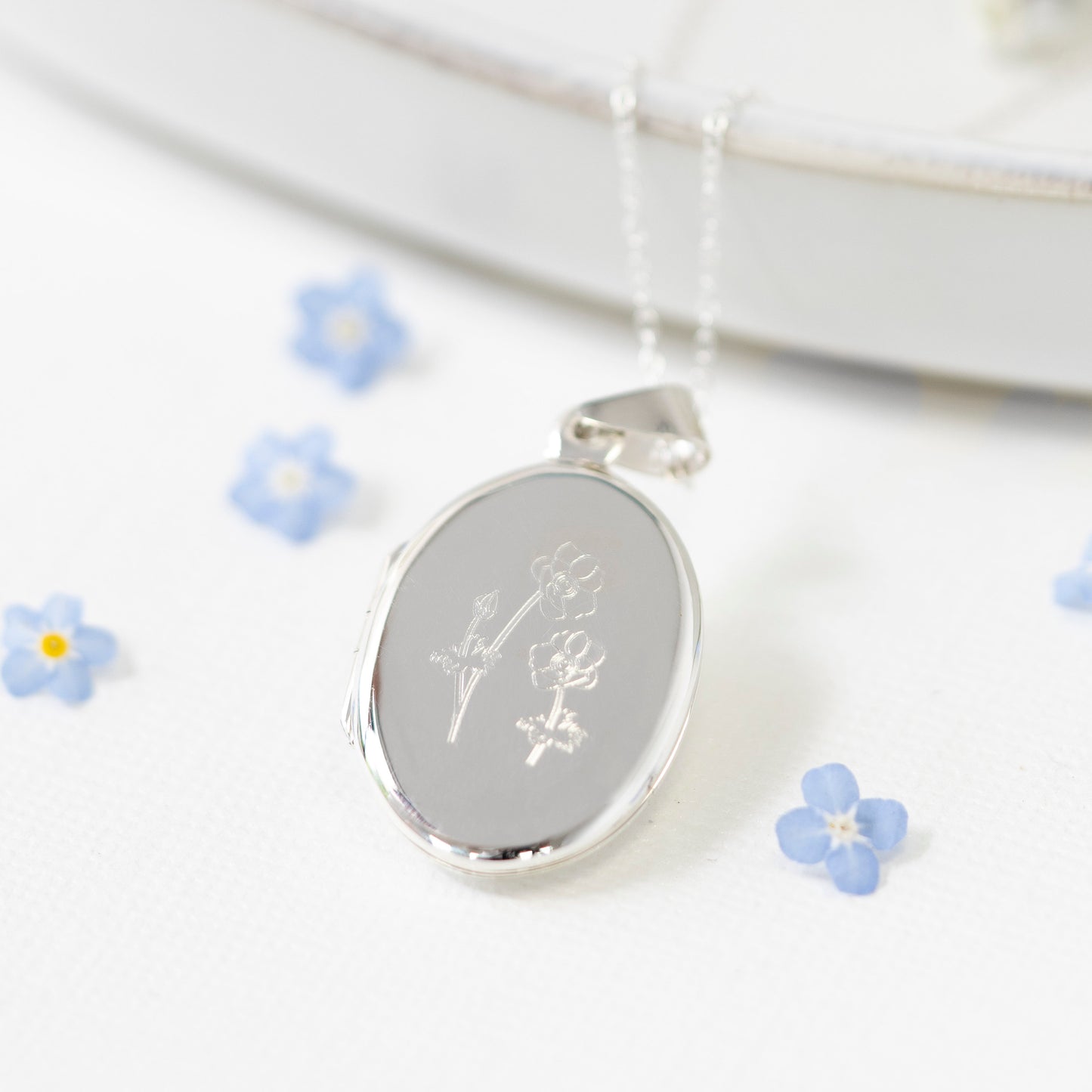 oval locket engraved with english wildflowers, perfect gift for a friend moving abroad, a mourning gift, or new beginnings gift.. holds two photographs and arrives giftboxed on a wildflowers gift card