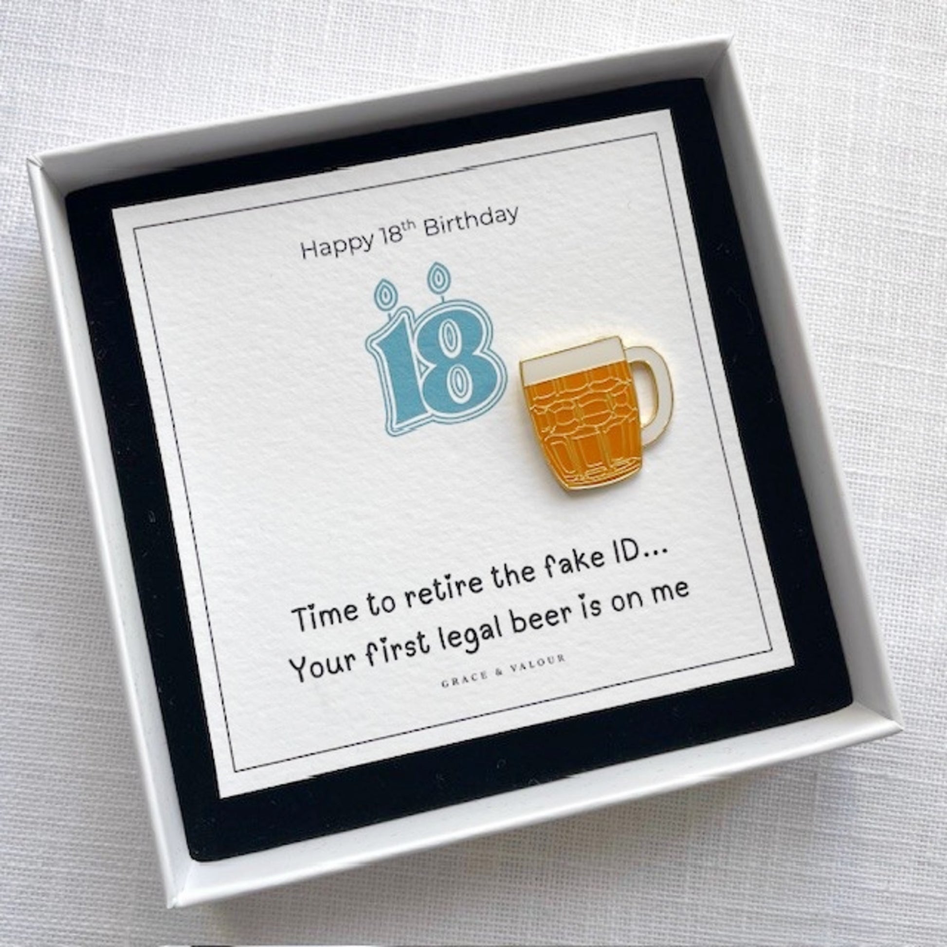 Gift box with a beer mug pin and birthday card on a light gray background