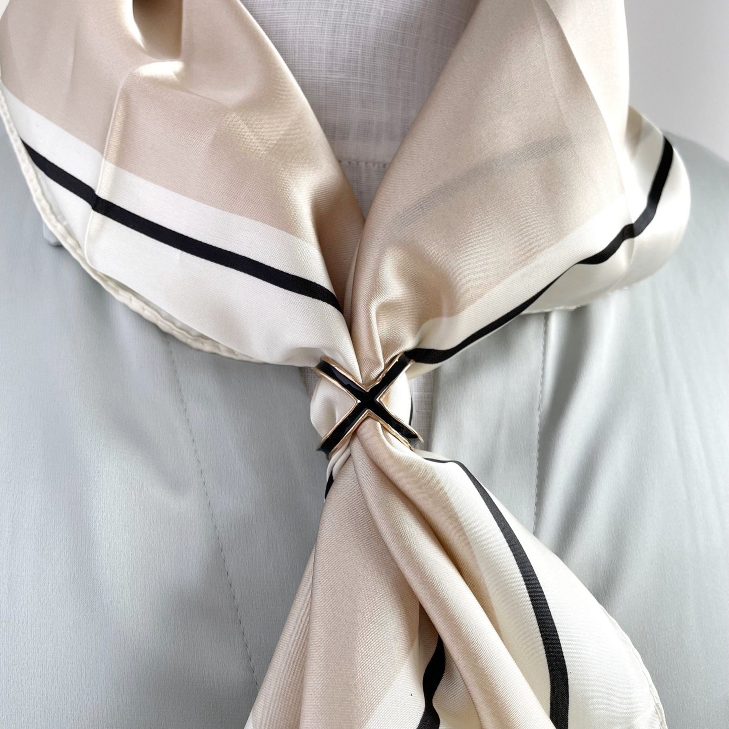 Black and gold scarf ring, four way, on a scarf worn by a model