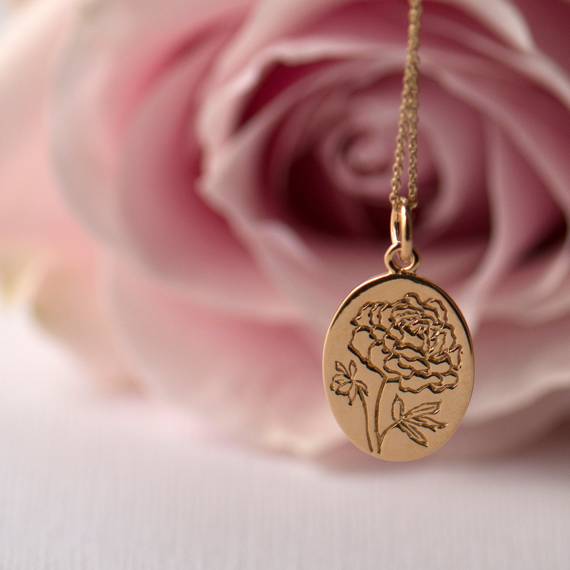 Elegant gold engraved peony necklace, the flower design is engraved onto a gold oval pendant on a matching chain.
