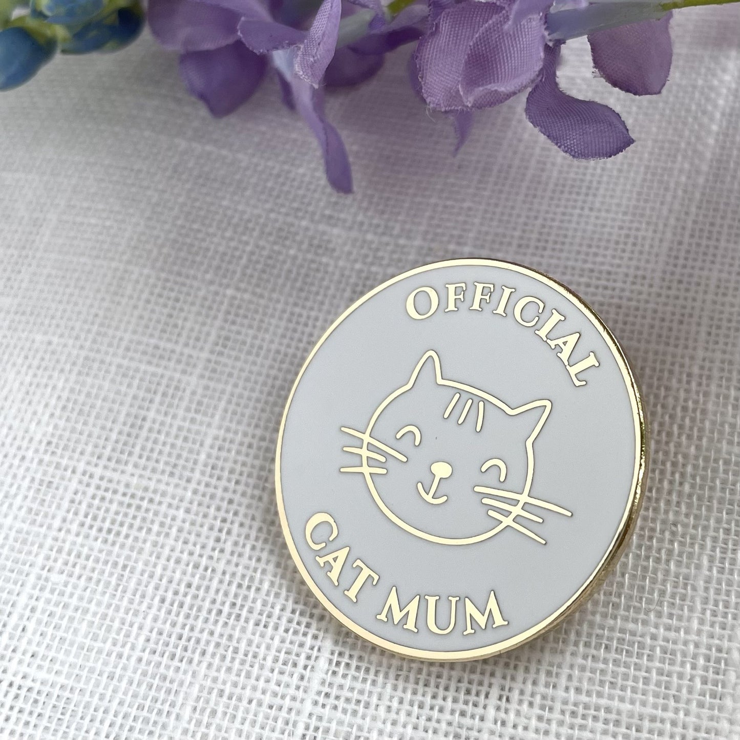 Circular badge with a cat illustration and 'Official Cat Mum' text on a textured fabric background.