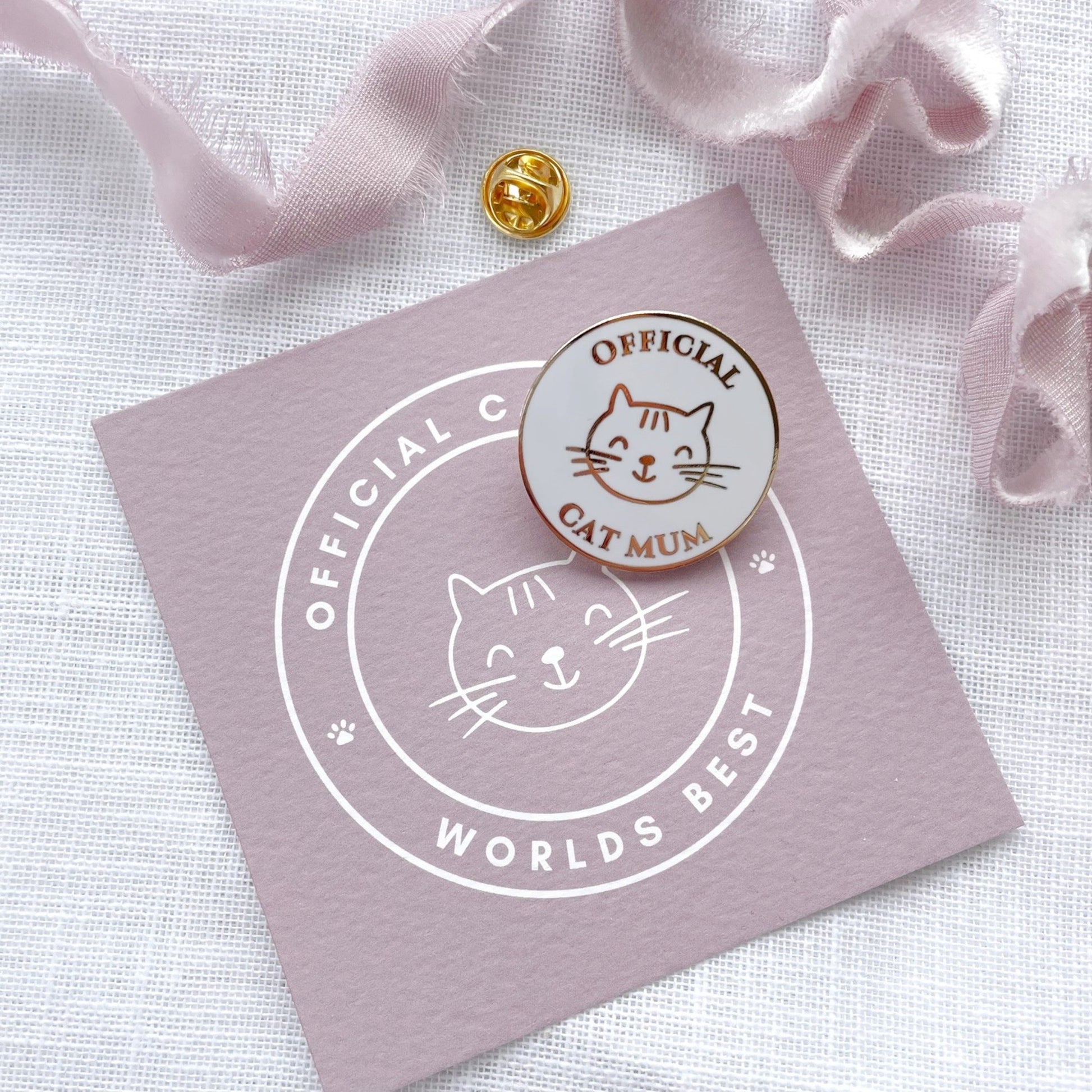Cat-themed pin on a pink card with decorative ribbons