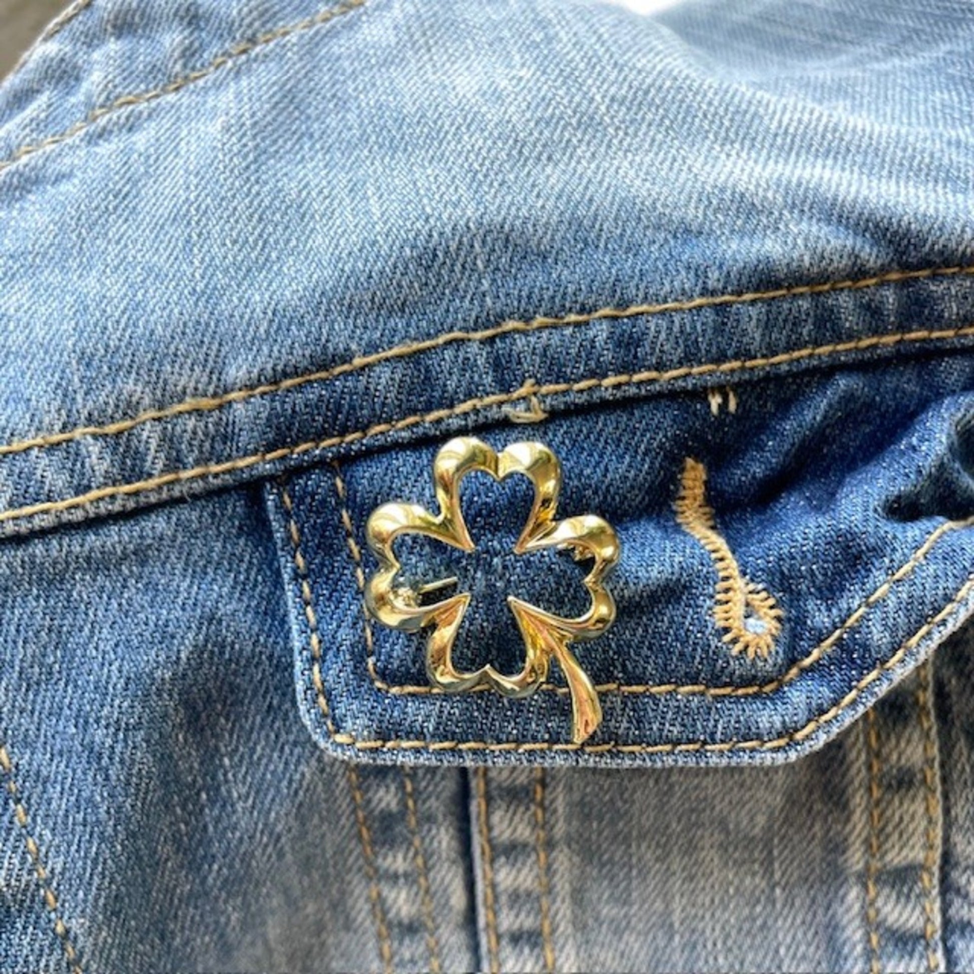 Gold clover brooch on a blue denim jacket