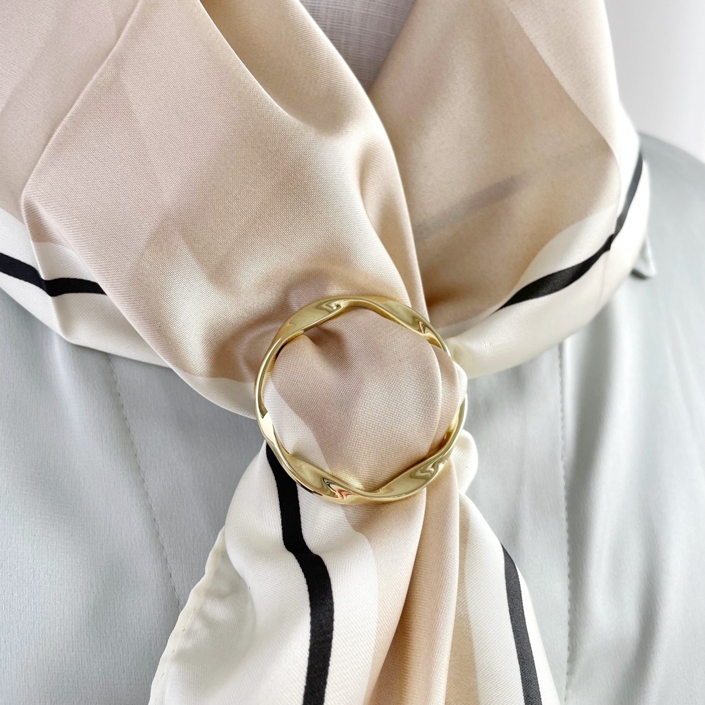 Scarf with a gold ring tie on a light gray background