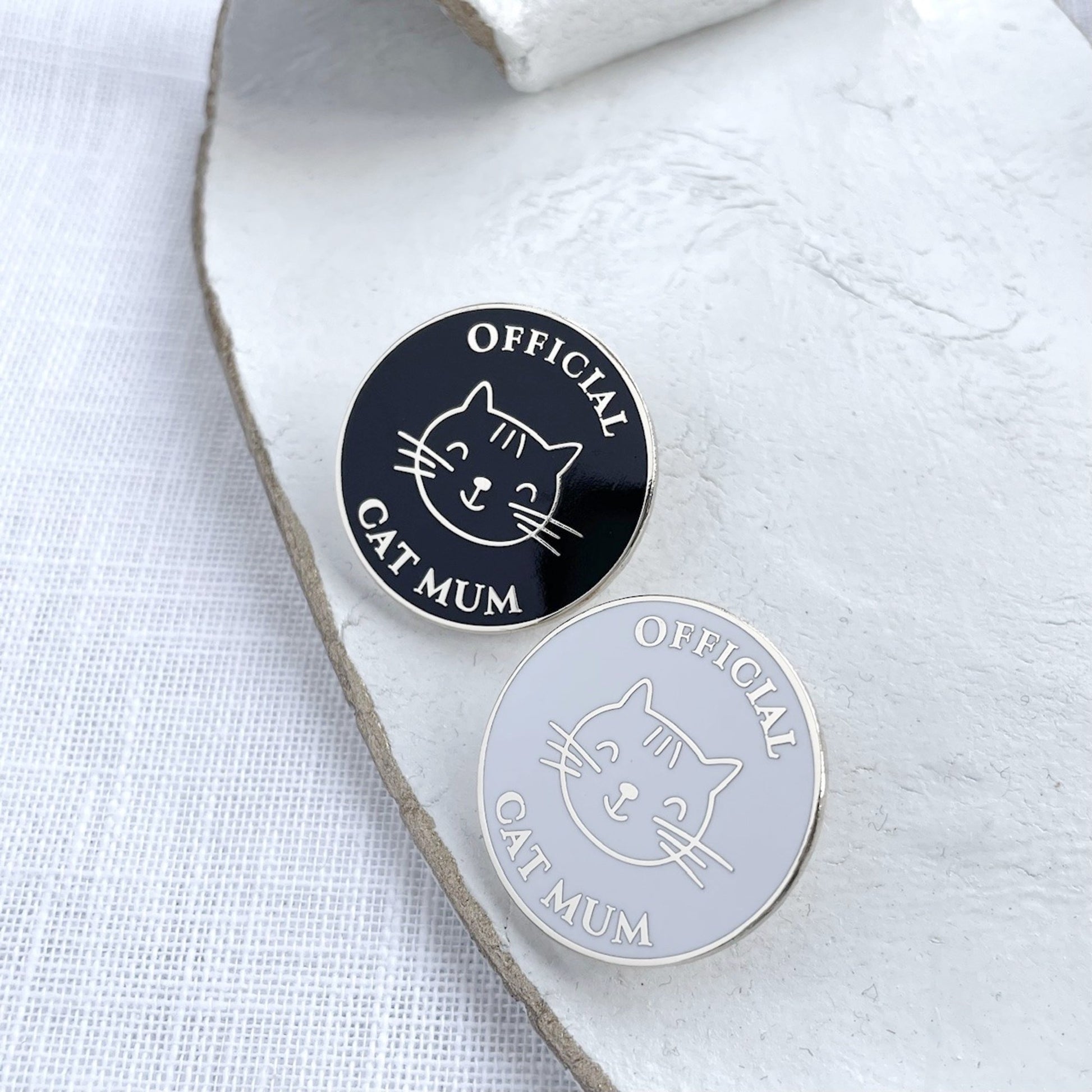 Two 'Official Cat Mum' pins on a white surface