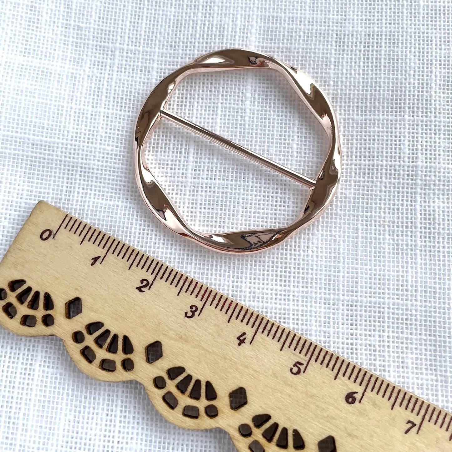 Rose gold Scarf ring on a wooden ruler for scale