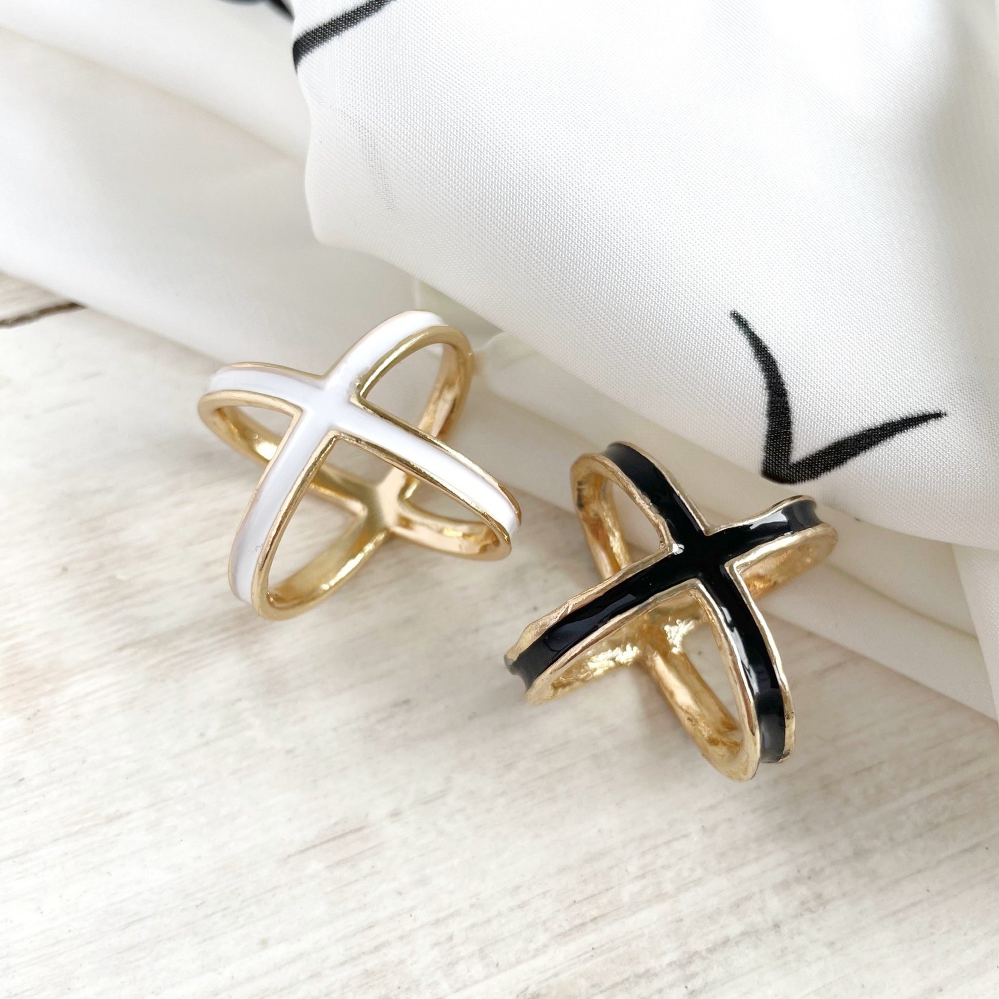 Two rings, one gold and one black and gold, on a white surface with a white cloth in the background.