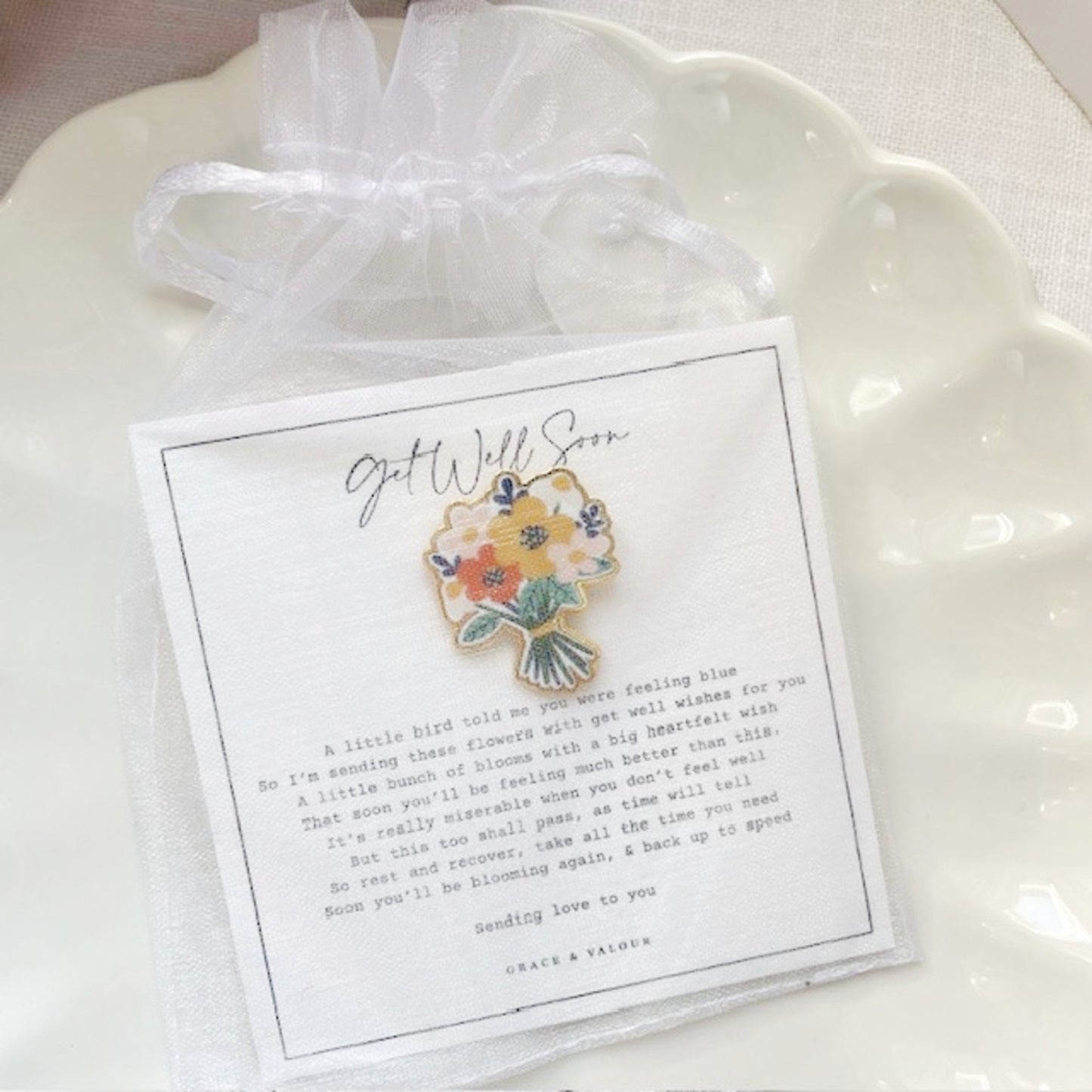 Floral brooch on a card with text on a white dish