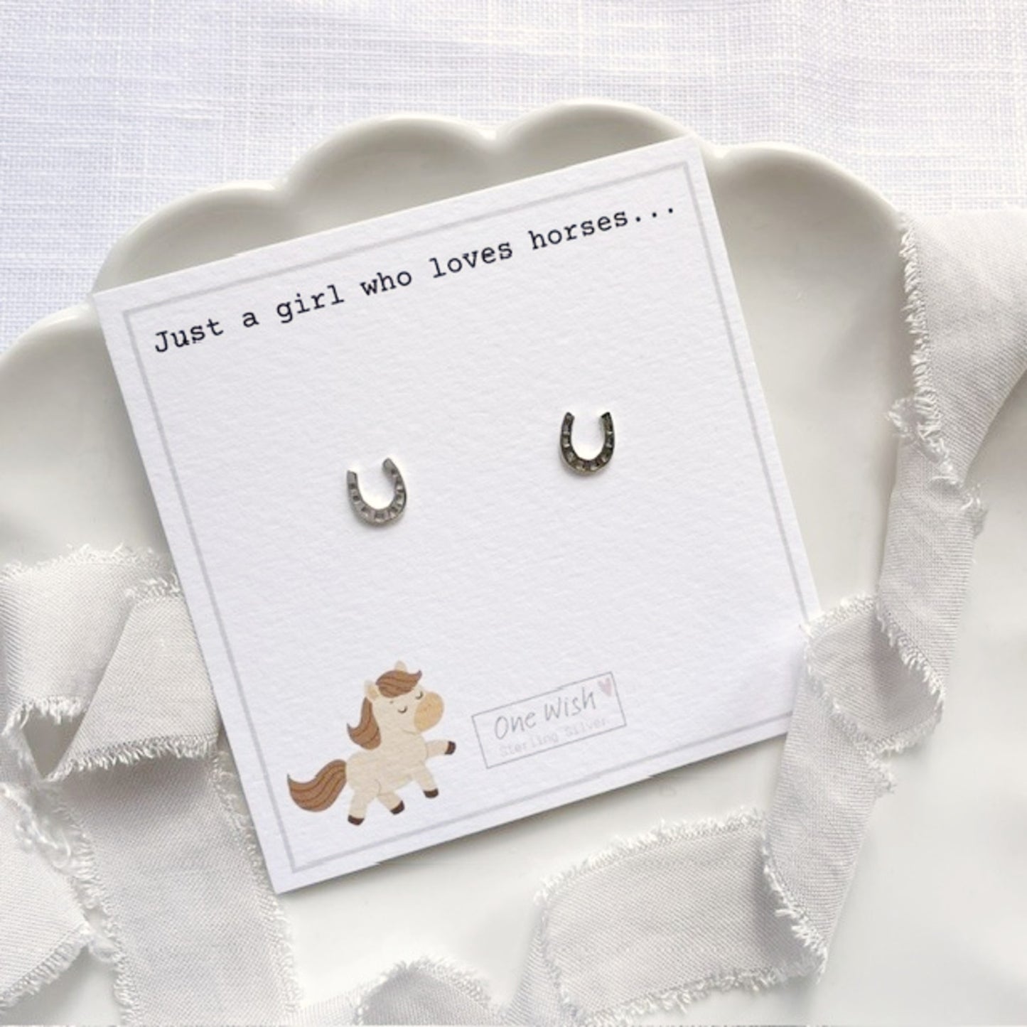 Horseshoe-shaped earrings on a card with text and a horse illustration.
