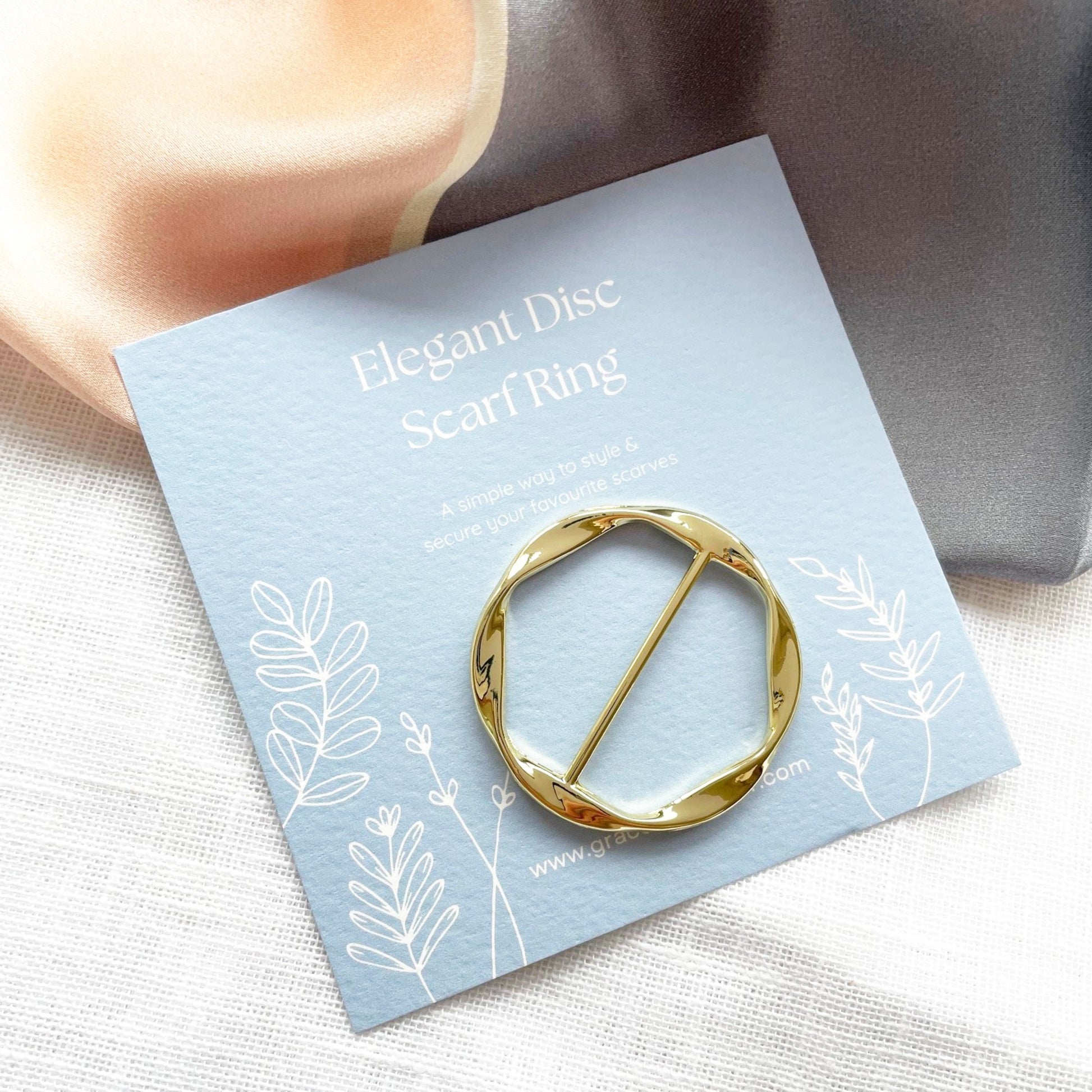 Gold scarf ring on a decorative card with floral designs