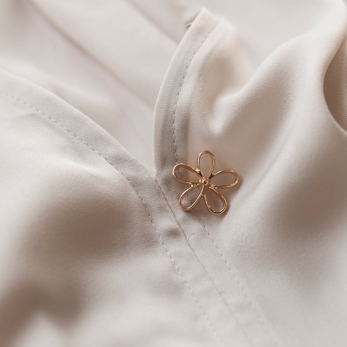 Gold flower modesty pin on low blouse