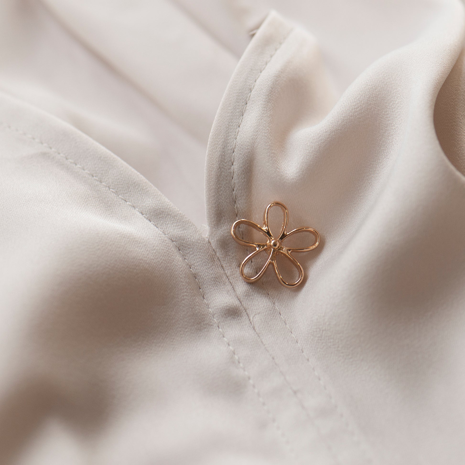 Gold flower modesty pin on low blouse