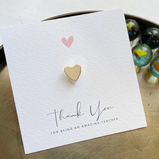 Heart-shaped pin on a 'Thank You for Being an Amazing Teacher' gift card