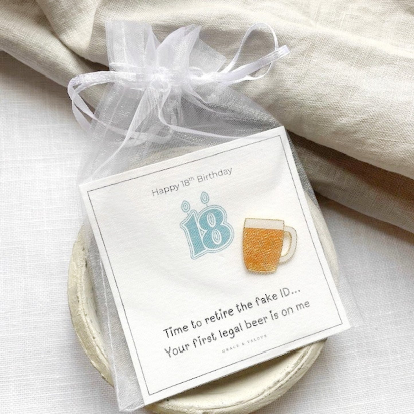 Gift with a beer-themed lapel pin and card on a bespoke gift card