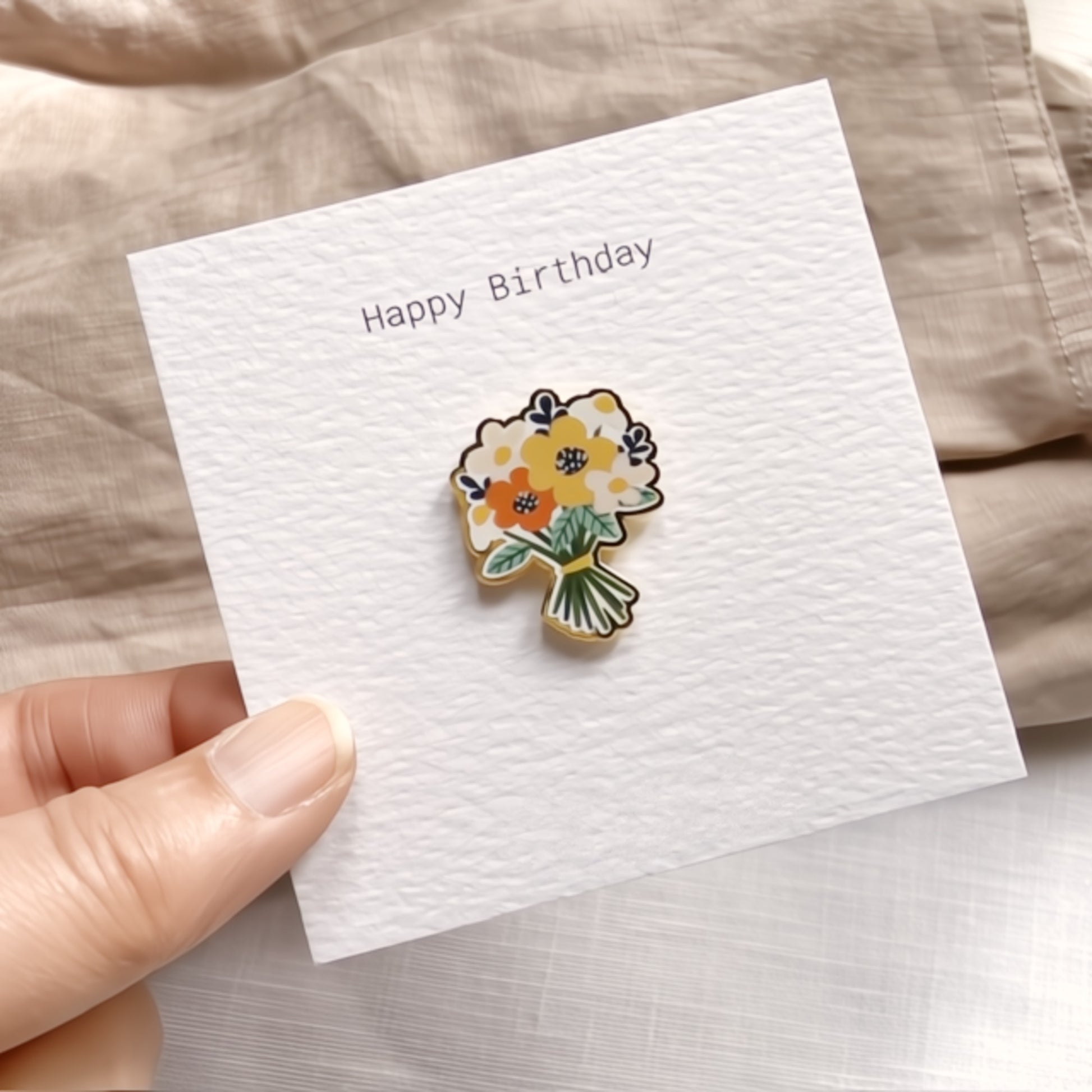Floral pin on a 'Happy Birthday' card held by a hand