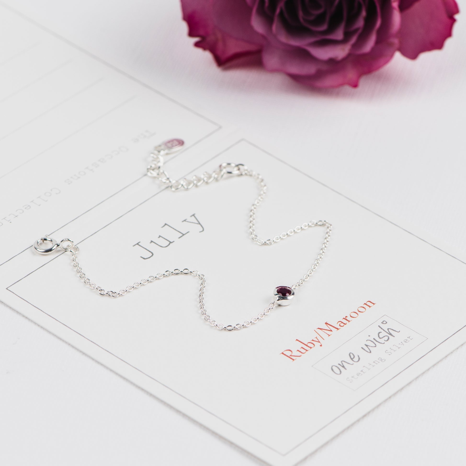 Silver bracelet with a red ruby gemstone on aJuly birth month gift card