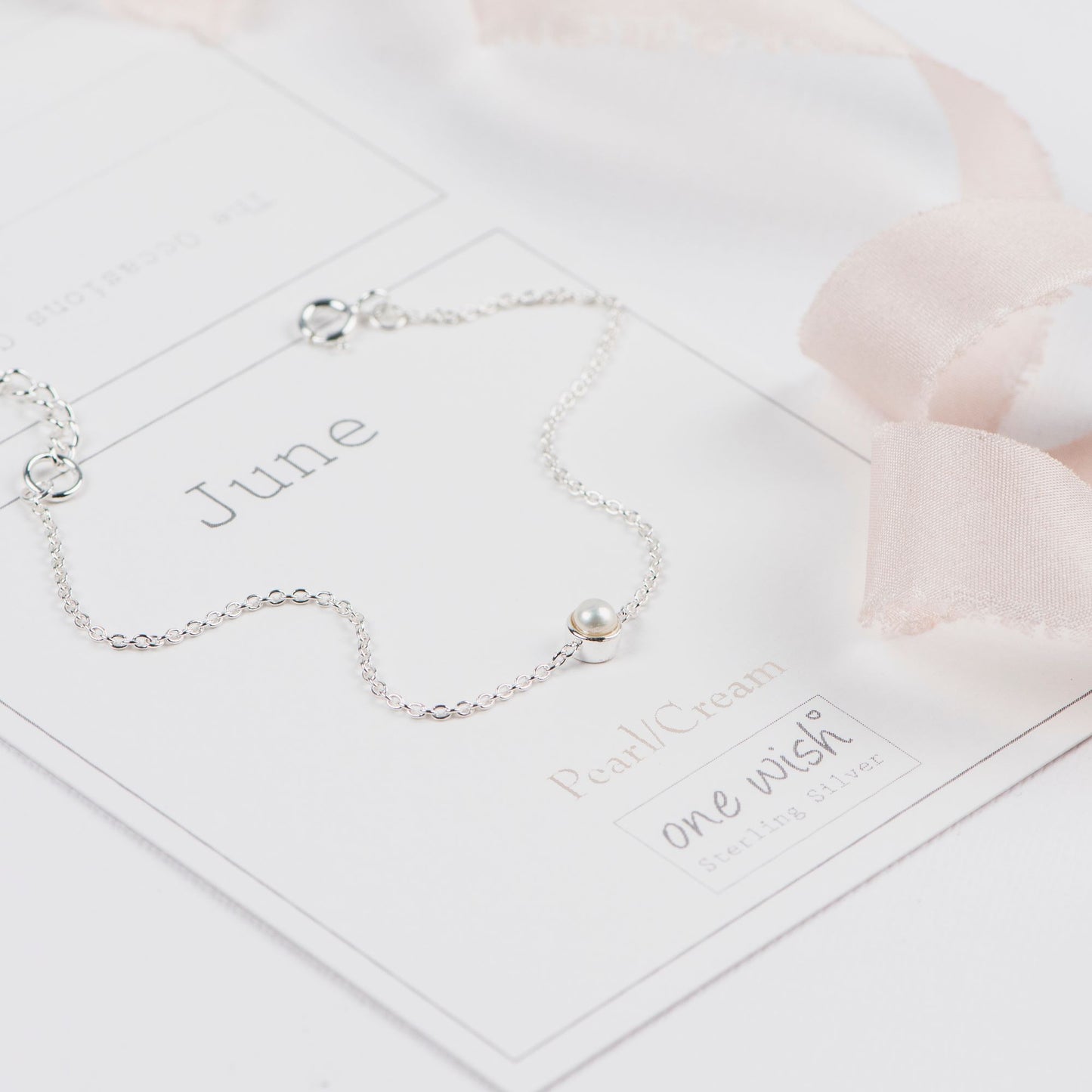 Silver June birthstone bracelet with a pearl on a white birthmonth june giftcard