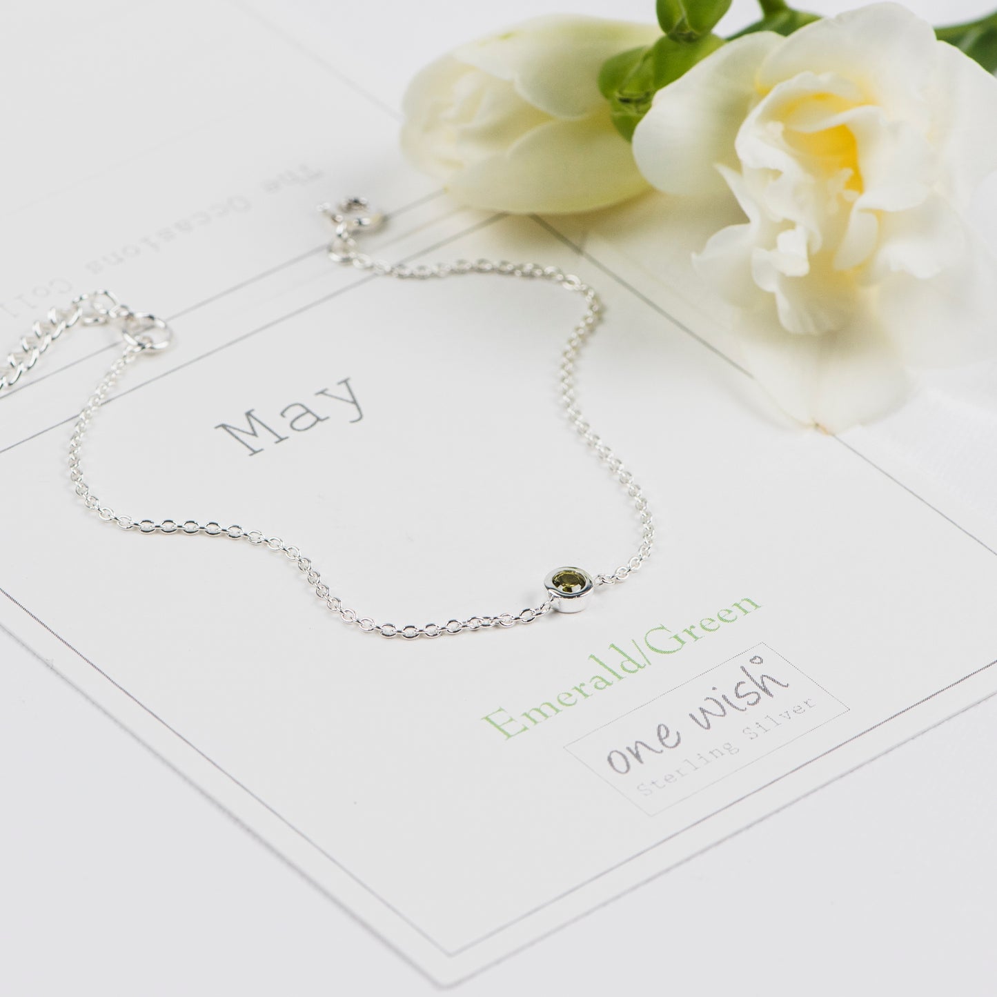 Silver bracelet with an emerald green gemstone on a May birthday gift card