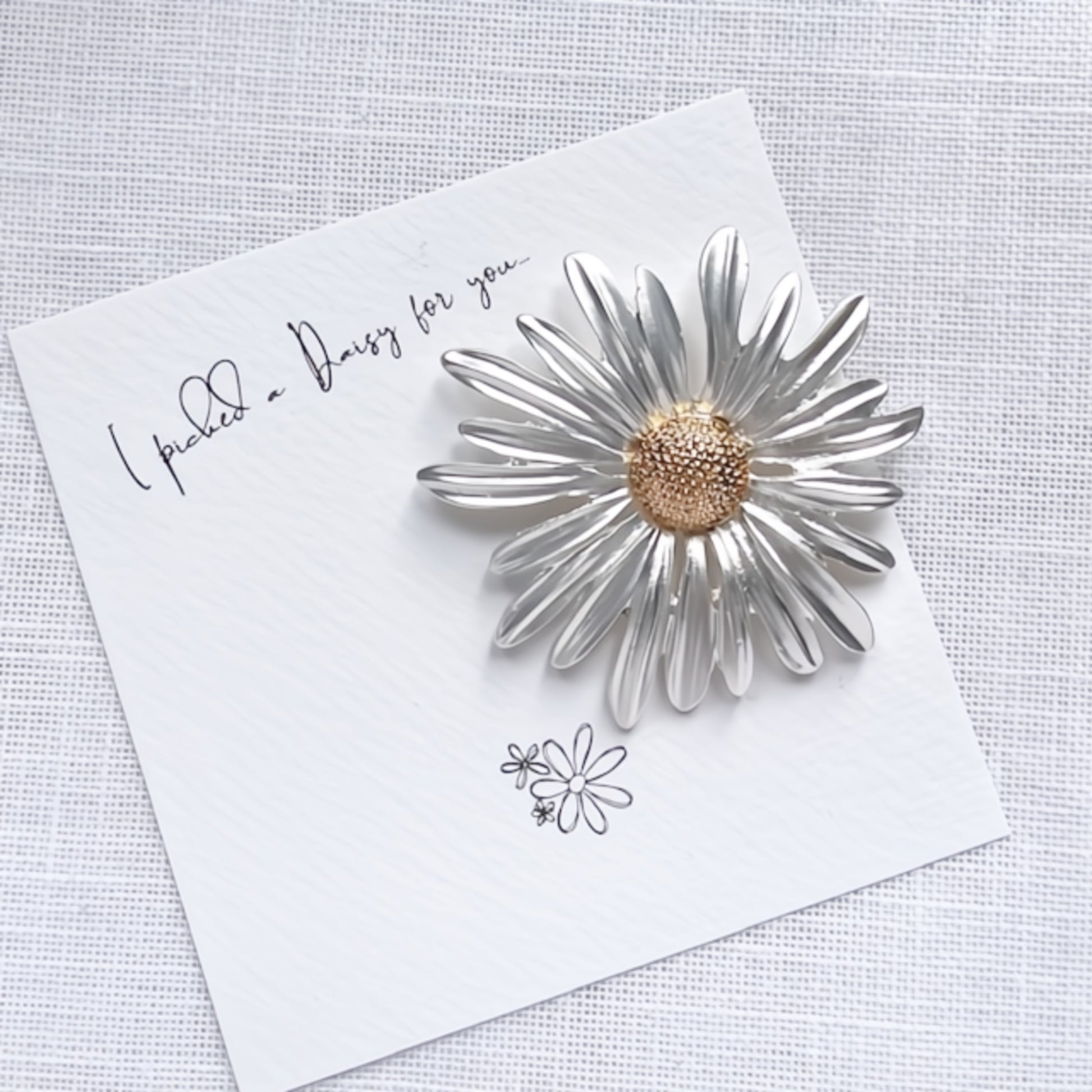 Silver daisy-shaped brooch on a bespoke 'picked a daisy for you' giftcard
