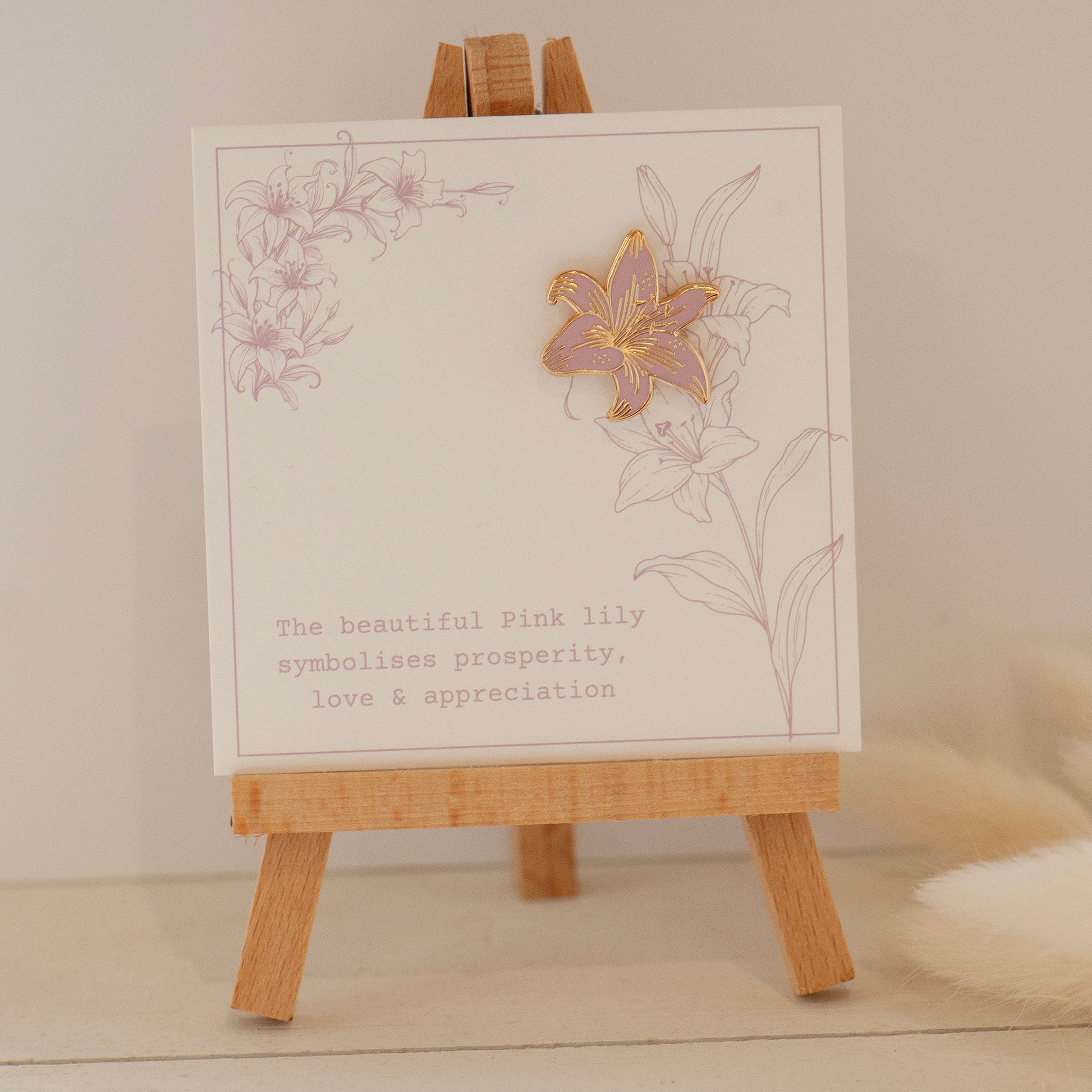 Pink and gold detailed stargazer lily enamel pin on my bespoke lily gift card which says 'The beautiful pink lily symbolises prosperity, love & appreciation'.  Gifts under £10, flower gifts