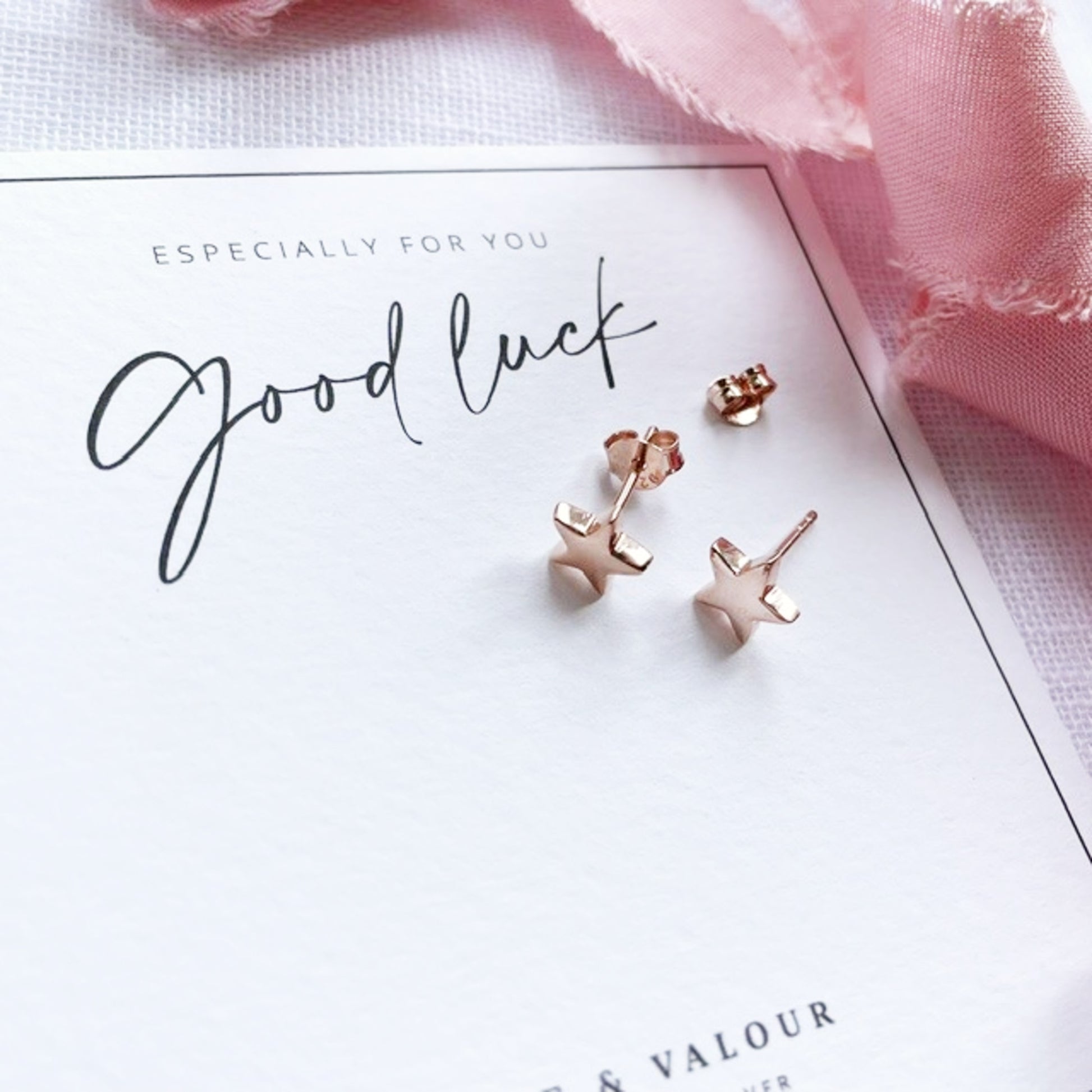 Rose gold star-shaped stud earrings displayed on a white card that reads 'Good luck' with 'Especially for you' above, styled with a pink ribbon.