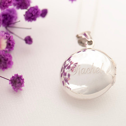 A round sterling silver personalized locket necklace with the name 'Rachel' engraved on the front in a flowing font.