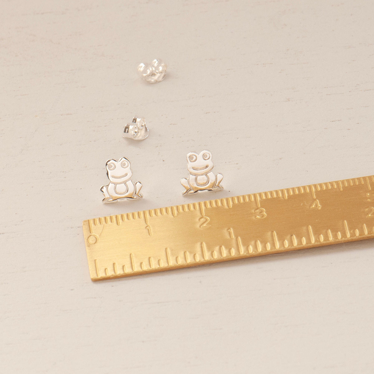 Sterling silver frog stud earrings with brass ruler to show dimensions