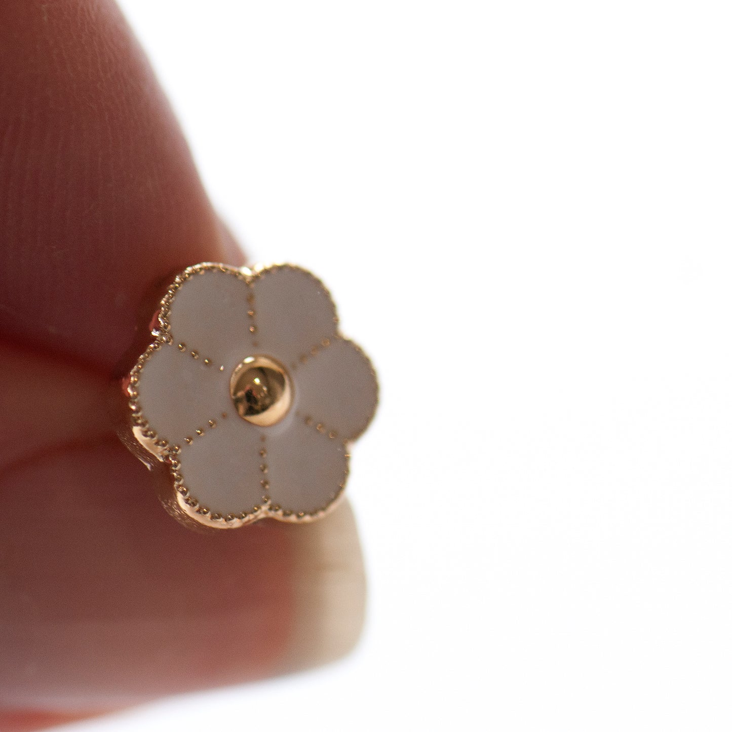 Tiny white enamel flower modesty pin close up, white enamel and gold detailing flower.