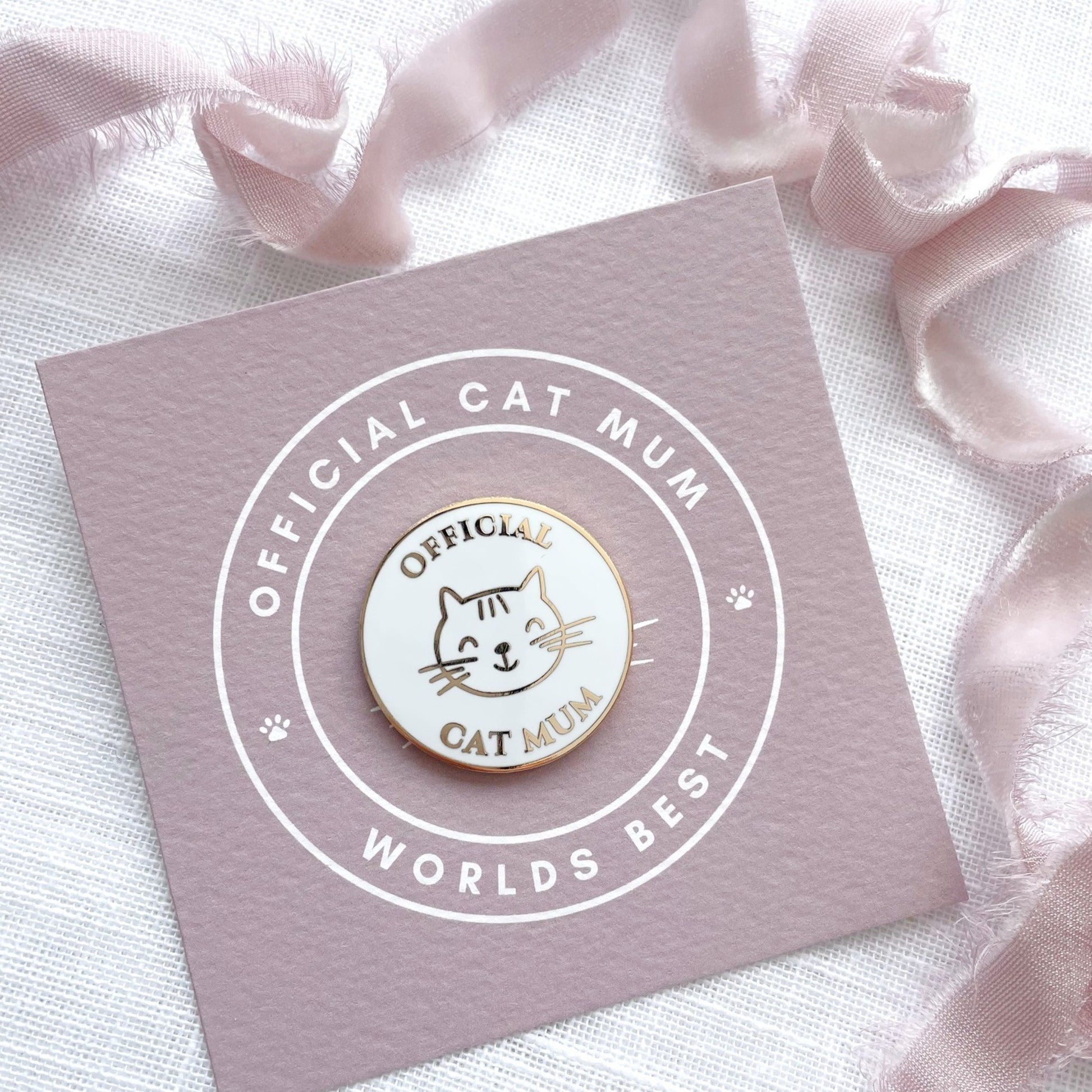 Pin with 'Official Cat Mum' text on a pink card with ribbons