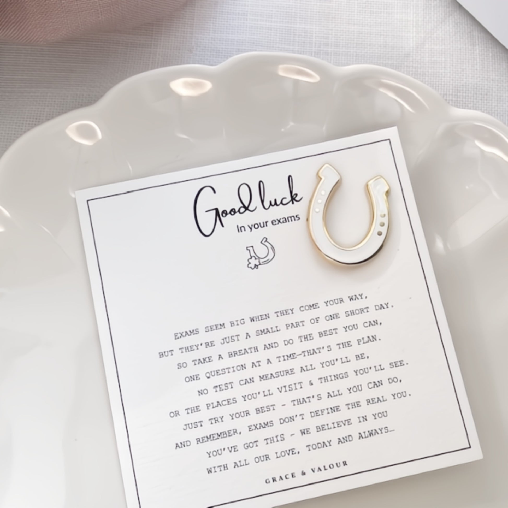 Good luck card with a horseshoe enamel pin on a white dish