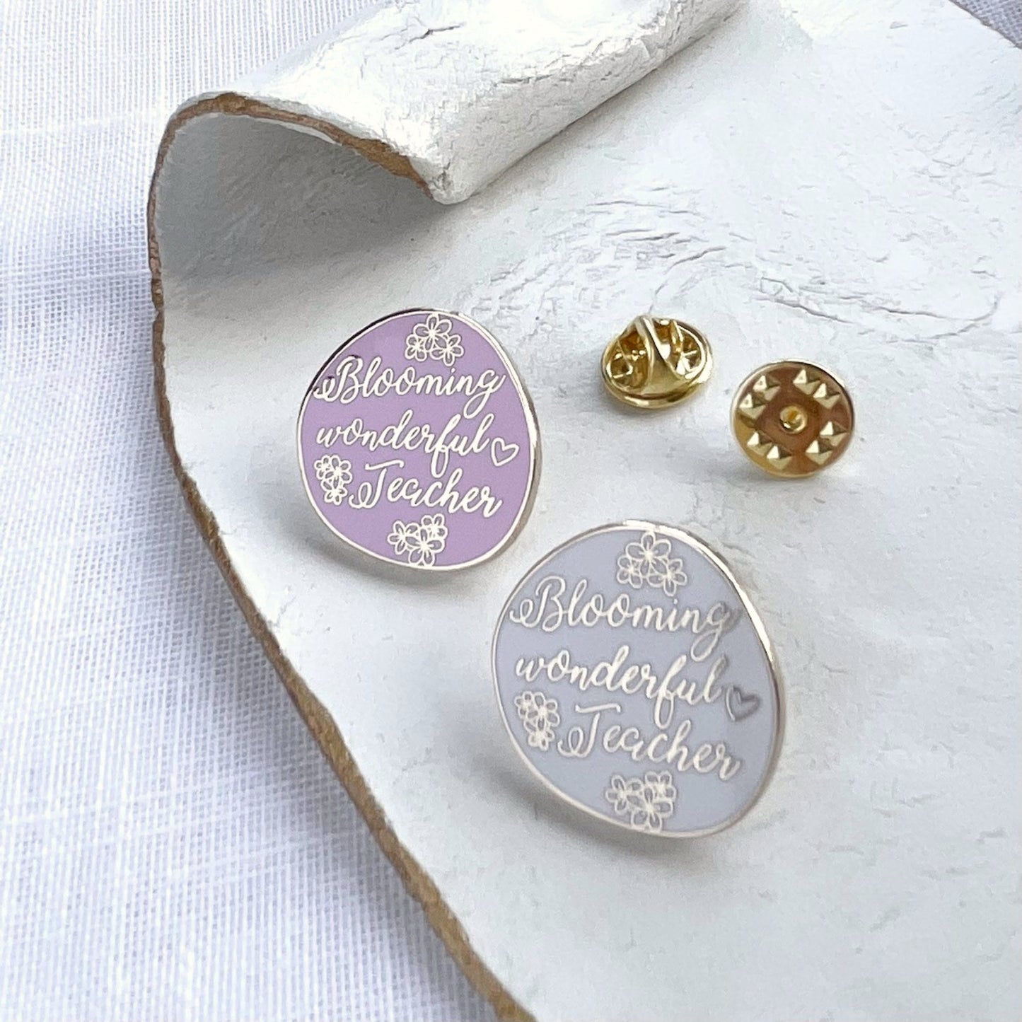 Two circular pins with 'Blooming wonderful Teacher' text on a white surface.