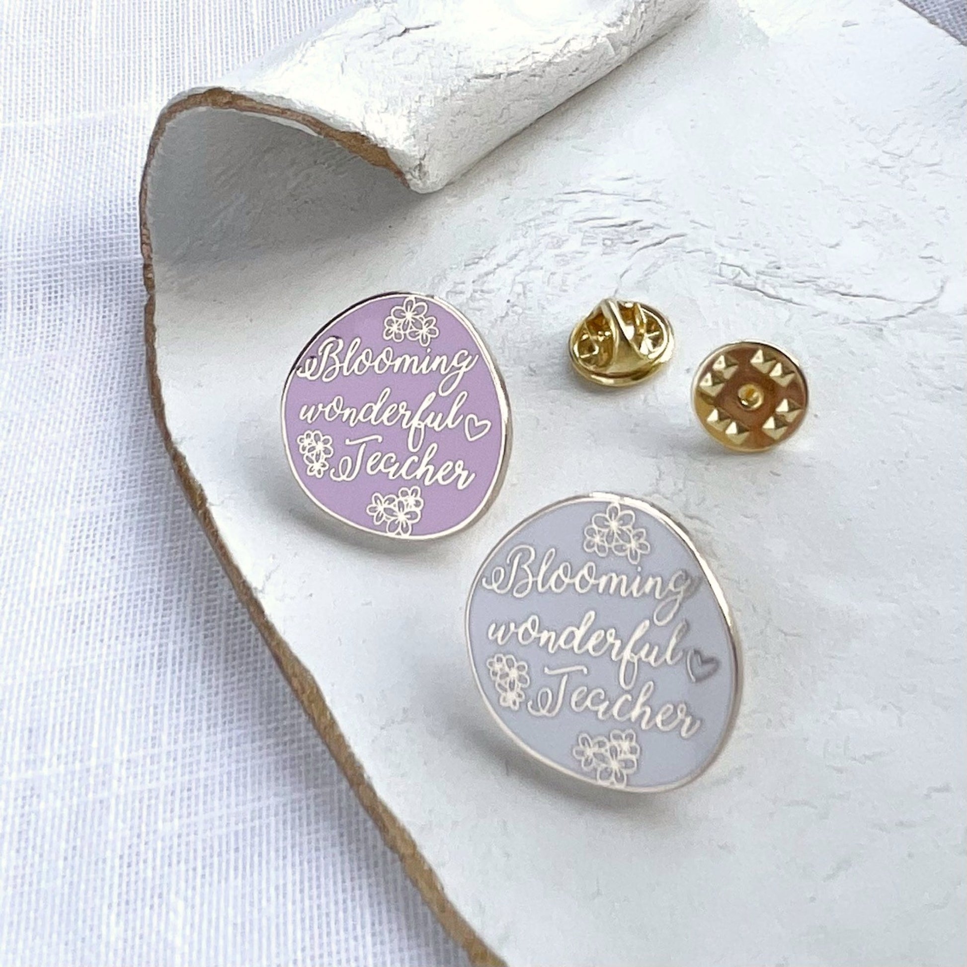 Two circular pins with 'Blooming wonderful Teacher' text on a white surface.