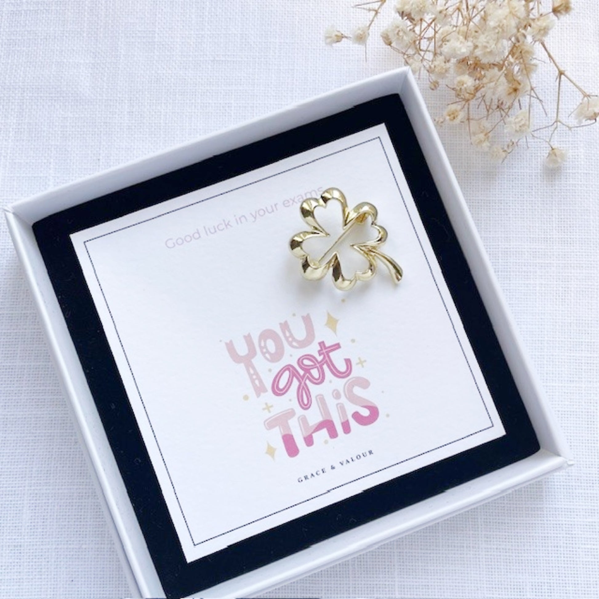 Gold four-leaf clover charm in a gift box with 'You got this' card.