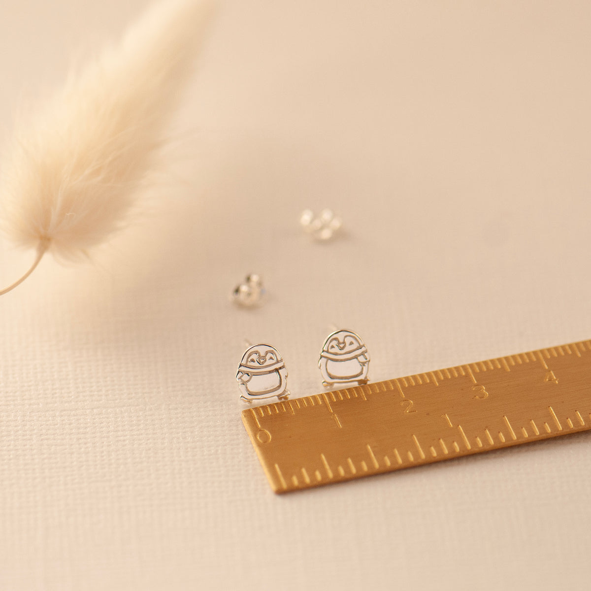 small cute penguin stud earrings with a ruler for scale sterling silver