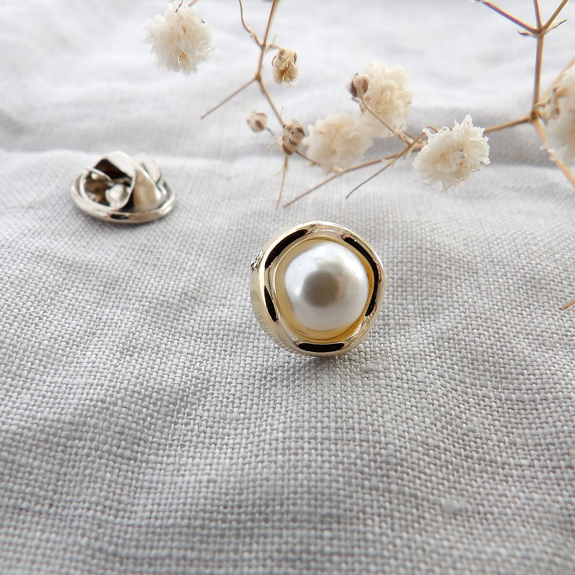 close up of pearl modesty pin with gold curvy surround