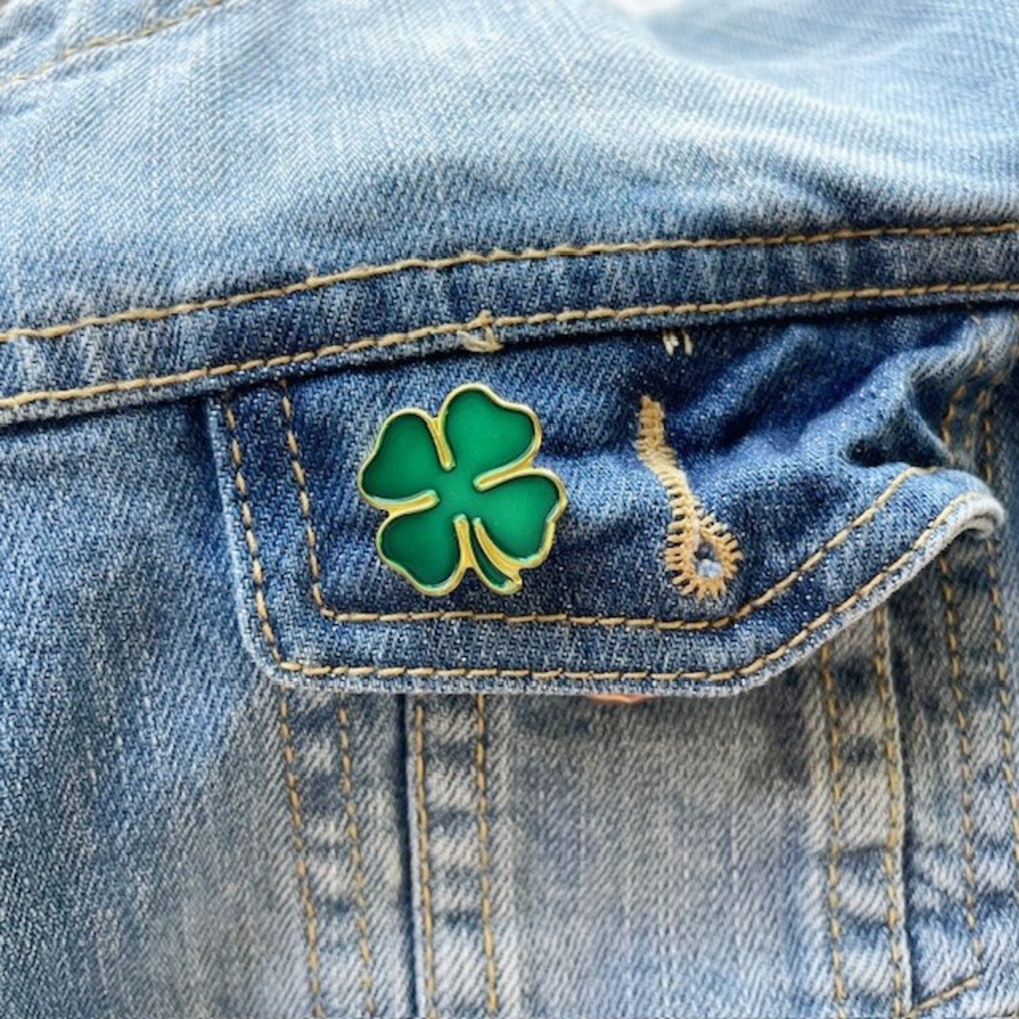 Green four-leaf clover pin on a denim jacket