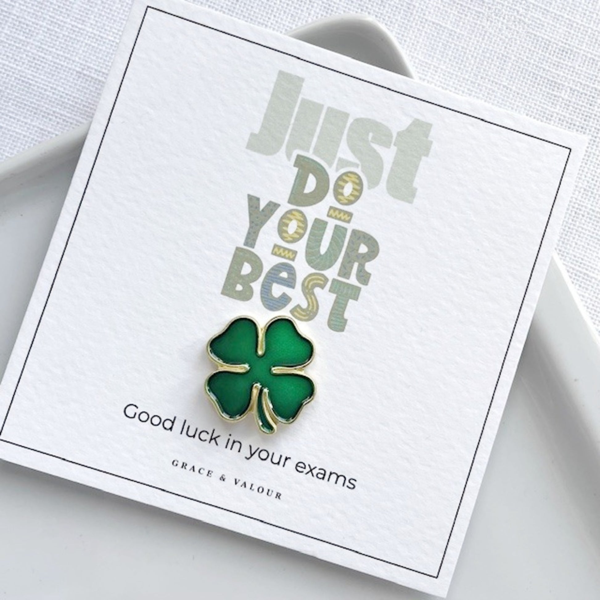 Green four-leaf clover pin on a card with motivational text