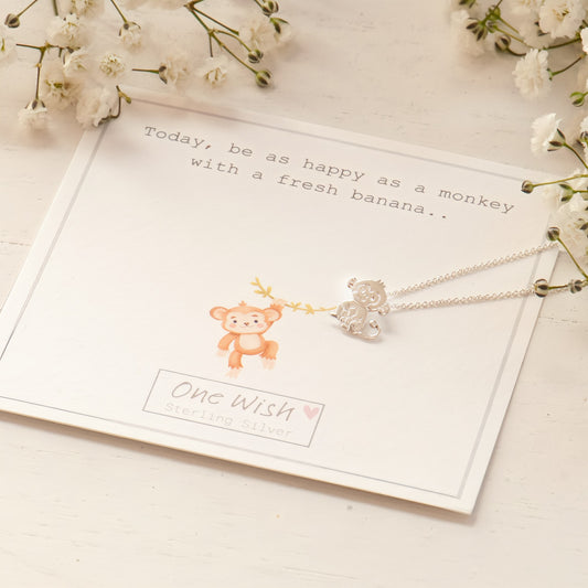 A sterling silver monkey necklace with a pendant monkey design, placed on a white gift card with a quote and a space for a personal message.