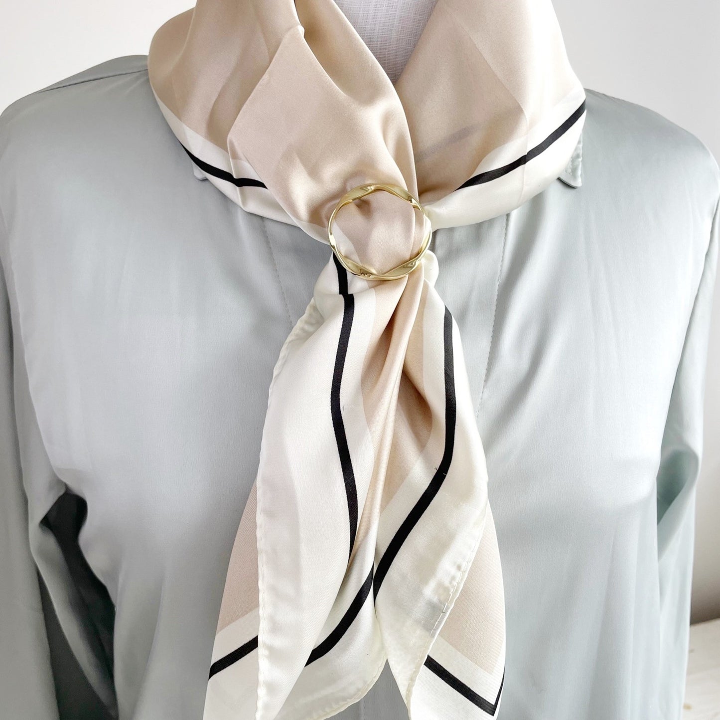 Gold scarf ring accessory on a gray background