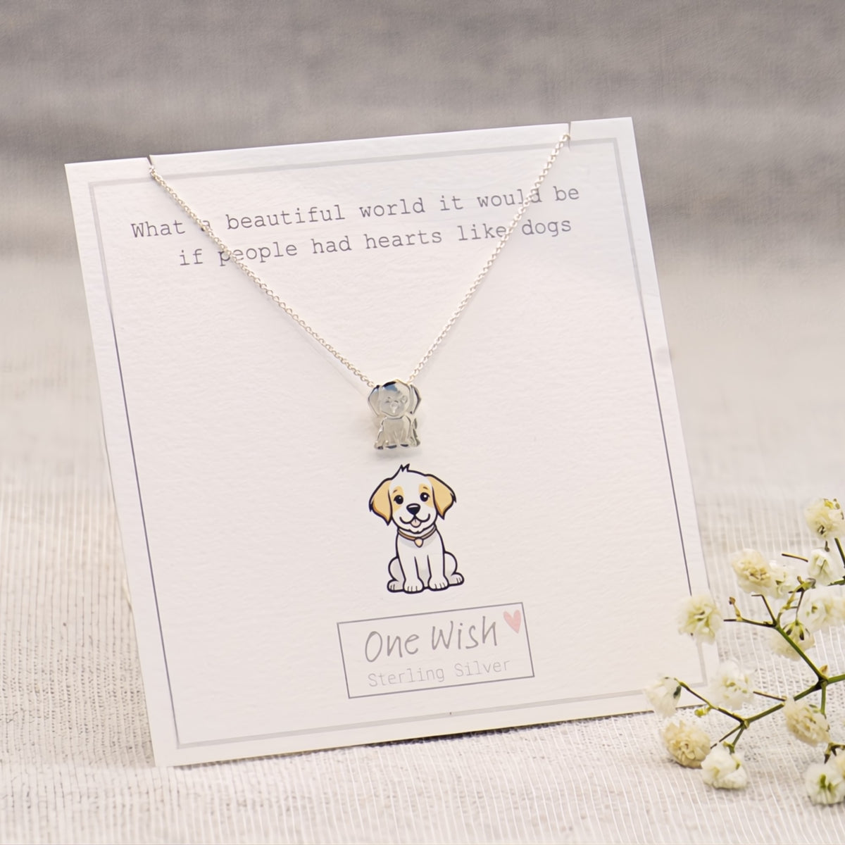 A sterling silver necklace with a small dog pendant displayed on a white gift card. The card features a cute illustration of the dog and the text 'One Wish Sterling Silver'.