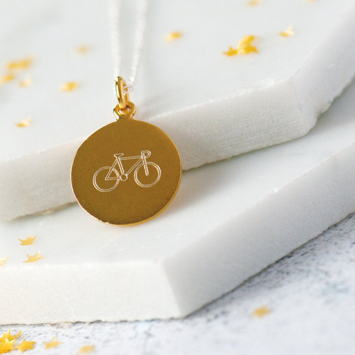 gold disc necklace engraved with an outline of a bicycle